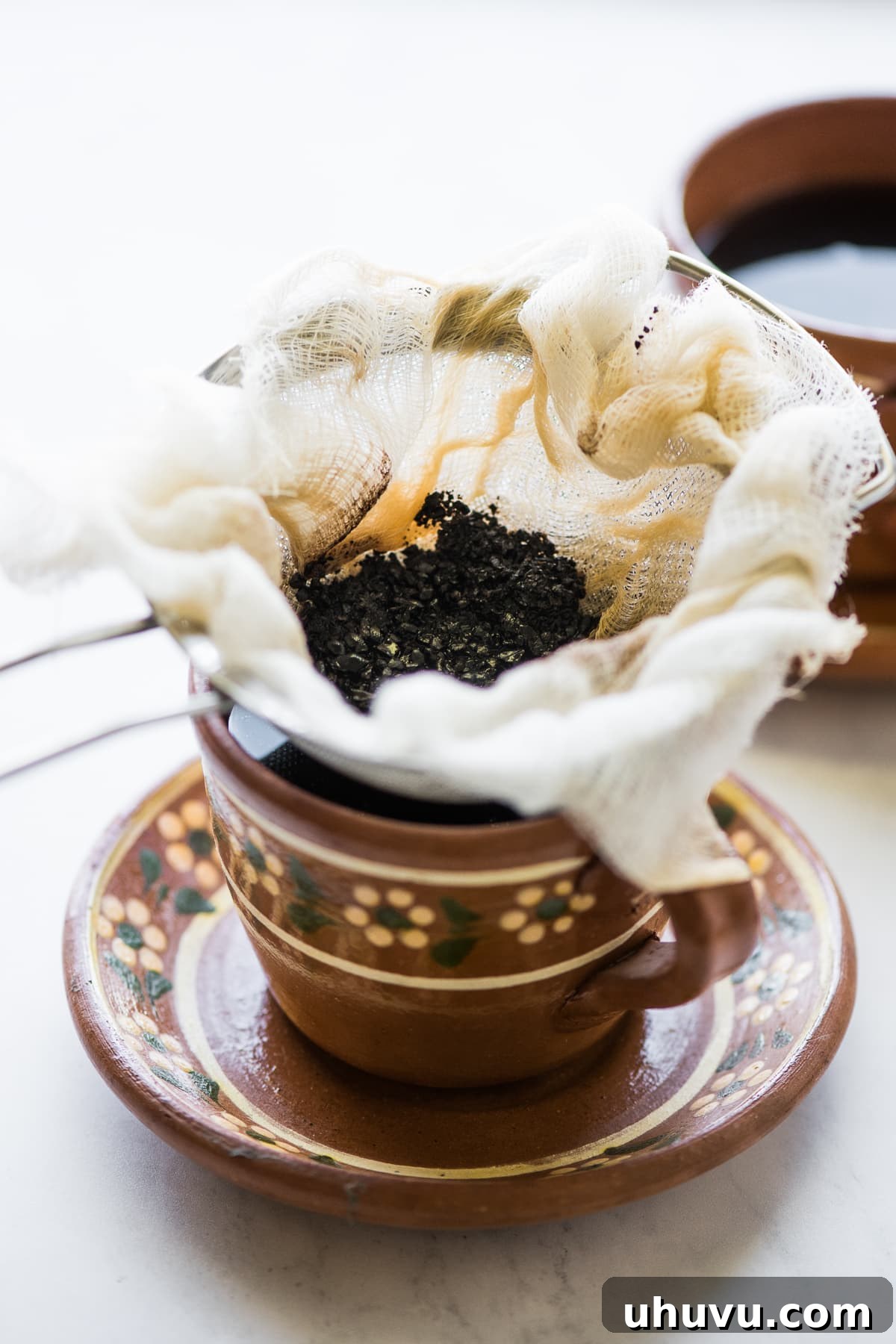 Spiced Olla Coffee 5 The process of straining freshly brewed Café de Olla to separate the coffee grounds and whole spices, ensuring a smooth cup.