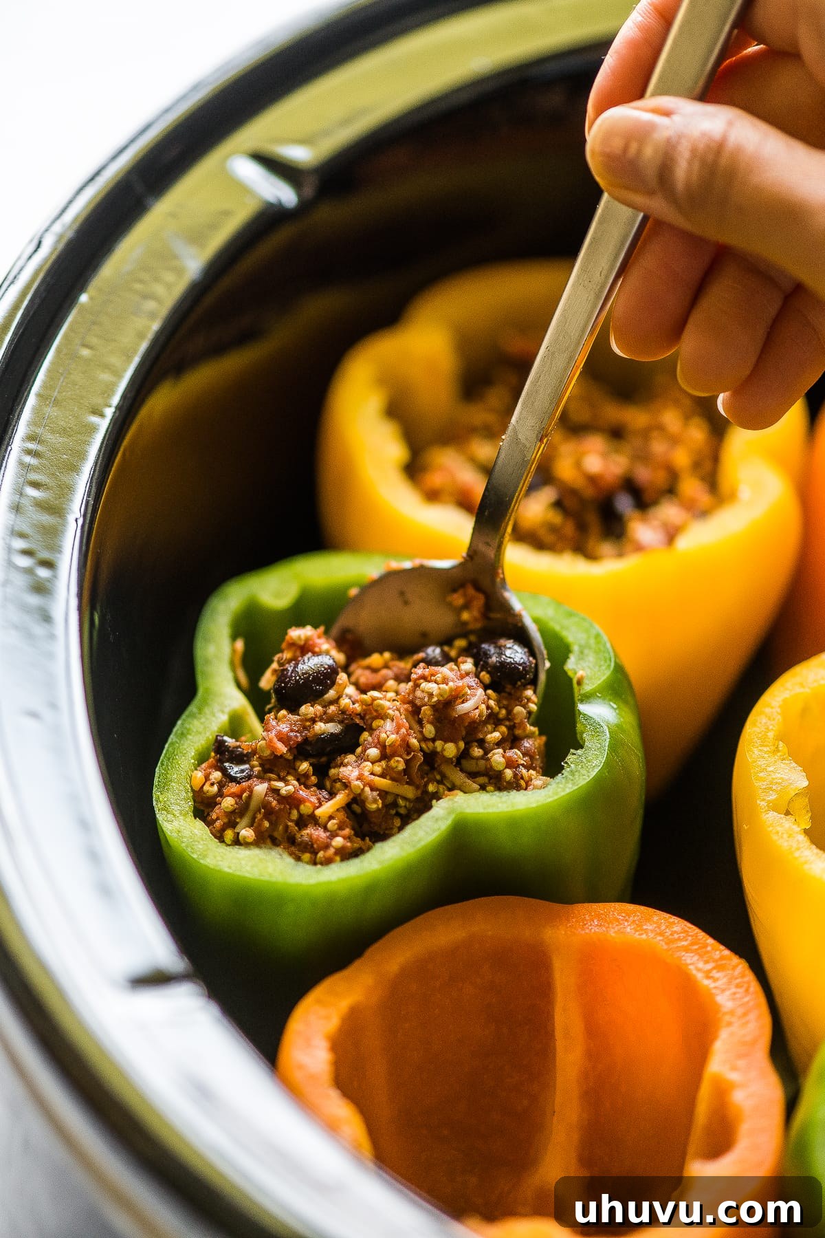 Slow-Cooked Stuffed Pepper Perfection 4 Bell peppers being stuffed with filling in a slow clooker.