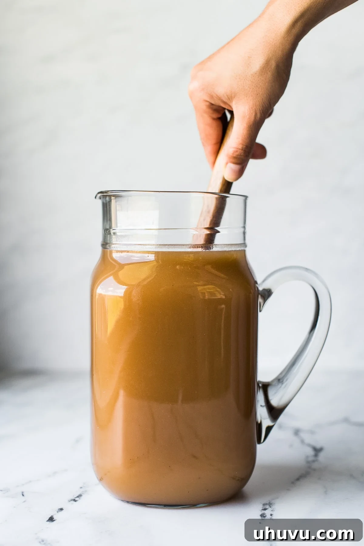 Tropical Tamarind Delight 7 Mixing agua de tamarindo in a pitcher with a spoon.