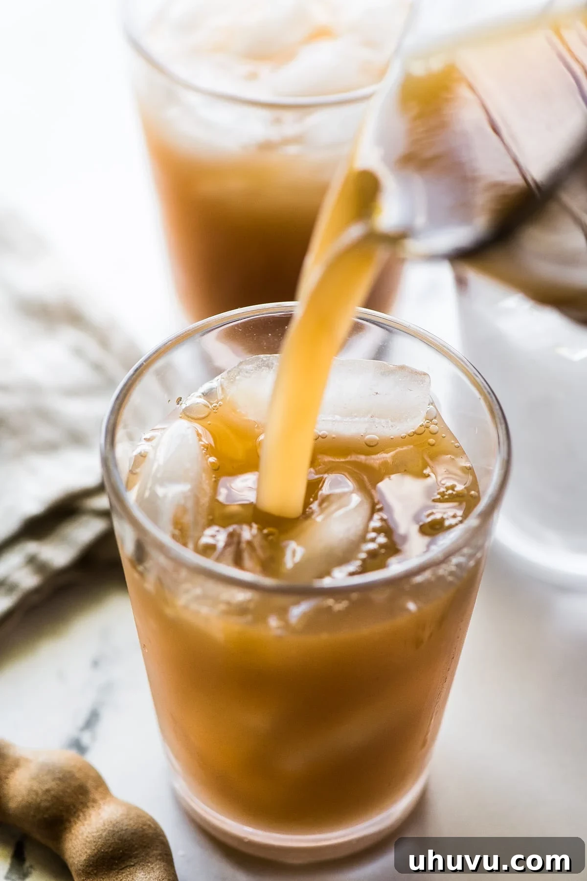 Tropical Tamarind Delight 8 Pouring agua de tamarindo drink into a cup with ice.