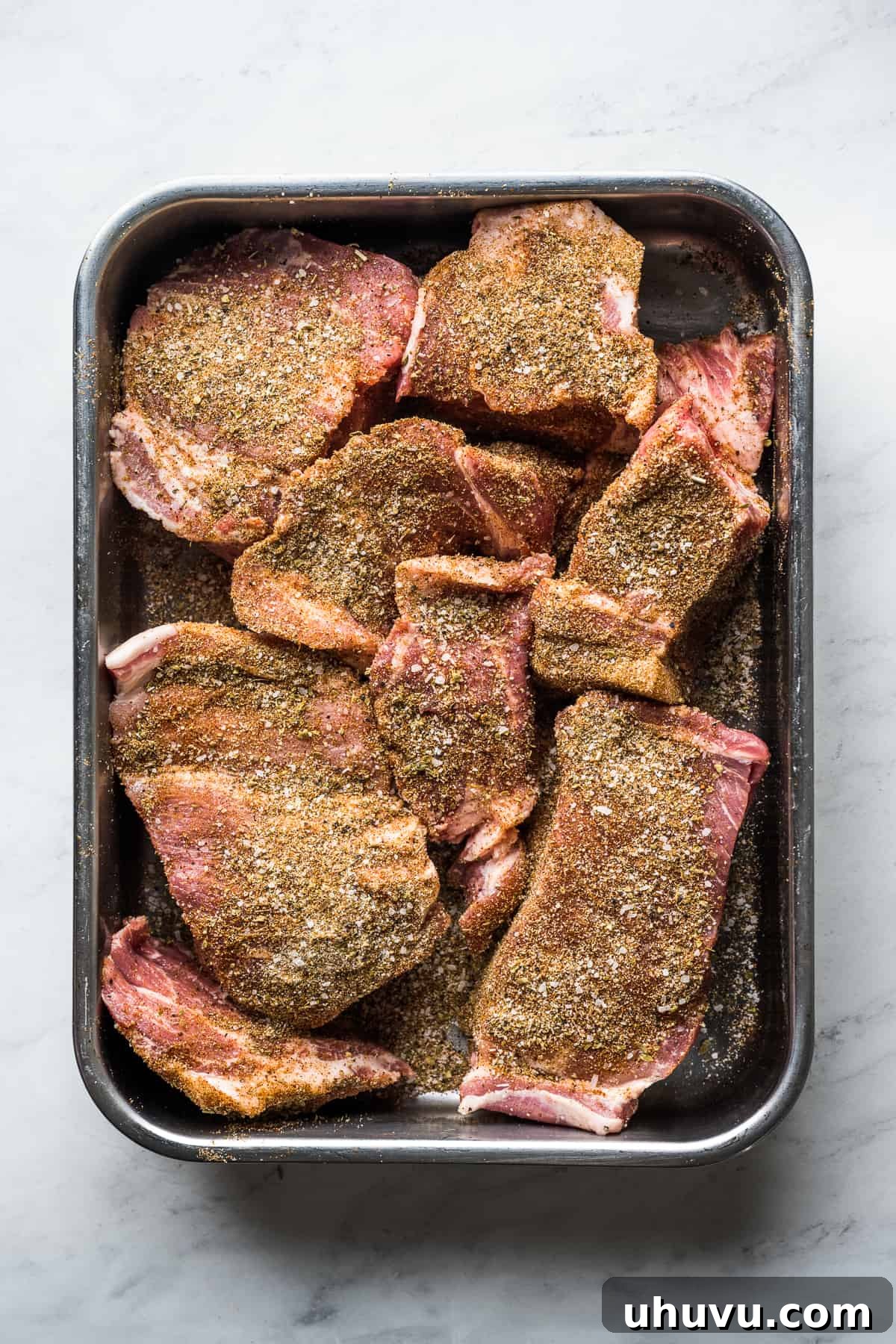 Slow-Cooked Pork Perfection 4 Large chunks of seasoned pork shoulder arranged neatly on a baking tray, ready for slow cooking.