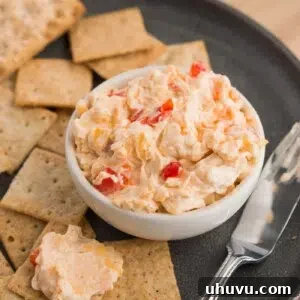 Homemade pimento dip in a small bowl with crackers for serving.