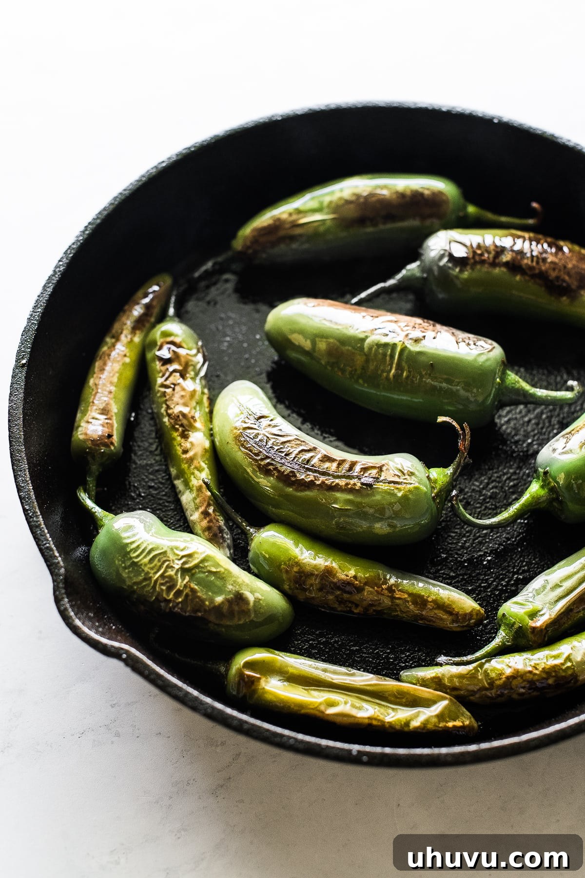 Smoky Mexican Chiles 4 Jalapeño peppers charring in a cast iron skillet for Chiles Toreados.