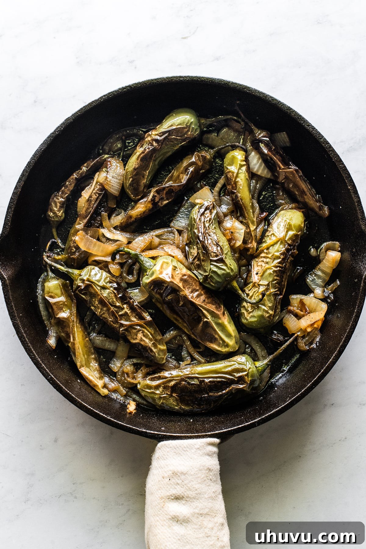 Smoky Mexican Chiles 5 Chiles toreados served in a traditional cast iron skillet, garnished with lime wedges.