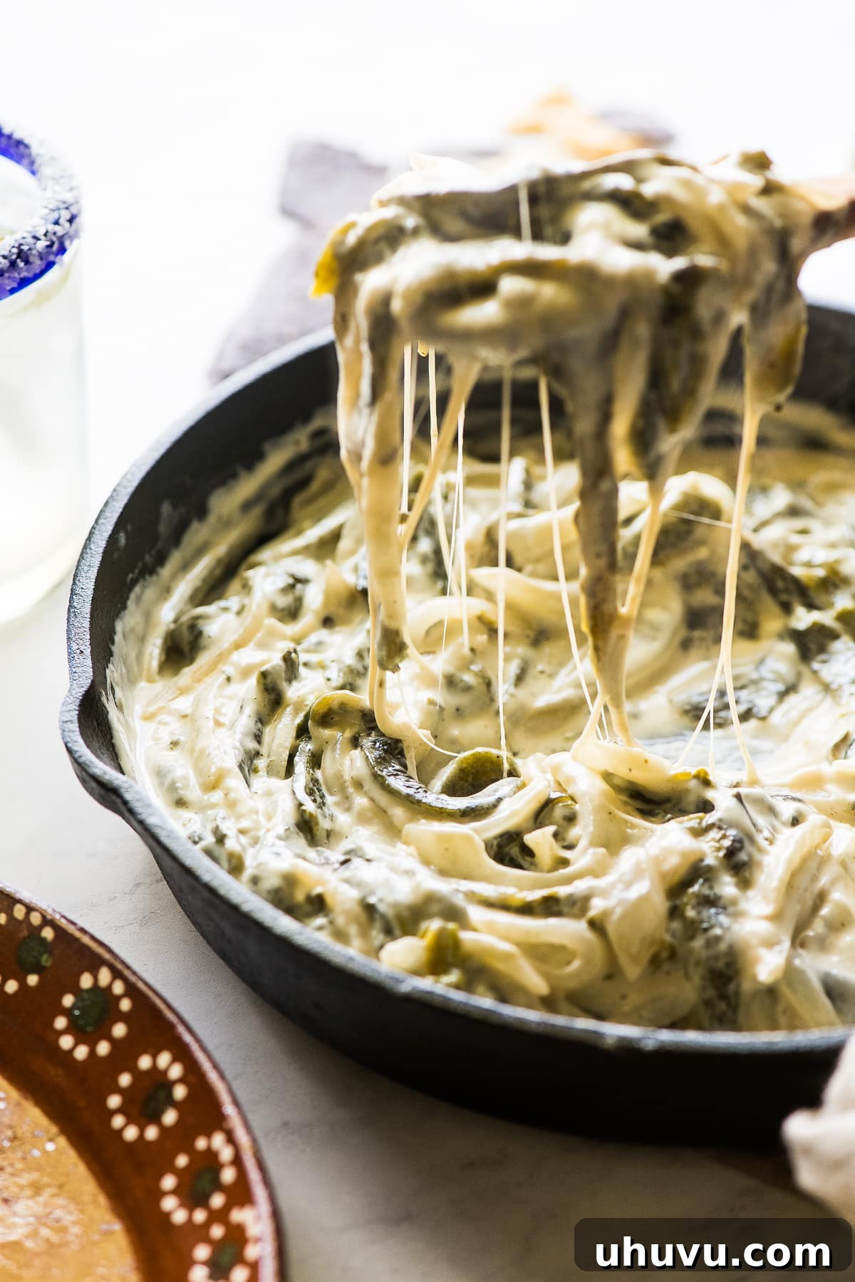 Close-up of stringy, melted Oaxaca cheese in Rajas con Crema, showing its luxurious texture.