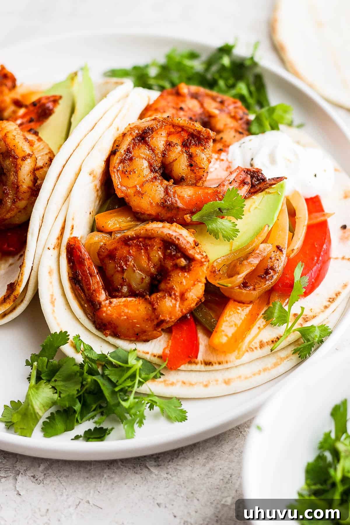 Vibrant Lime Shrimp Fajitas 7 Platter of warm flour tortillas brimming with delicious shrimp fajitas, garnished with fresh avocado slices and cilantro, ready for serving.
