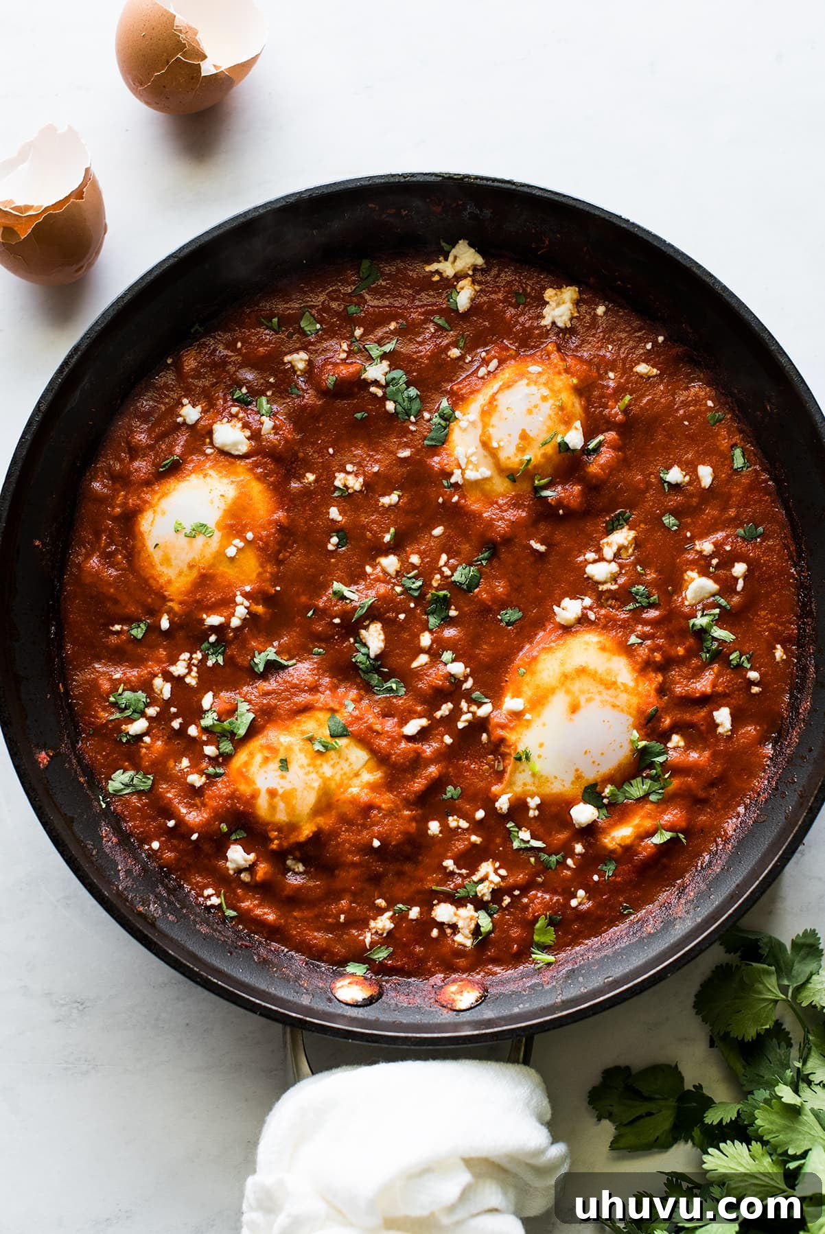 Salsa-Poached Eggs 11 A skillet of huevos ahogados topped with cilantro and queso fresco.