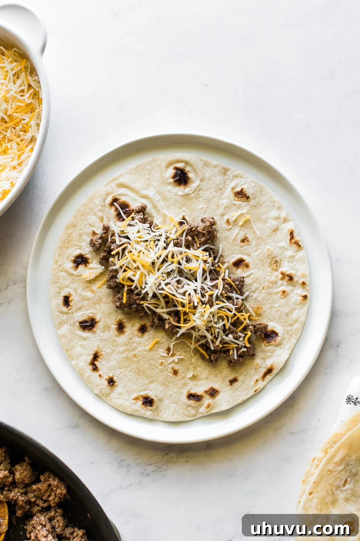 Hearty Beef Enchilada Fiesta 5 A flour tortilla with ground beef filling and shredded cheese on top.