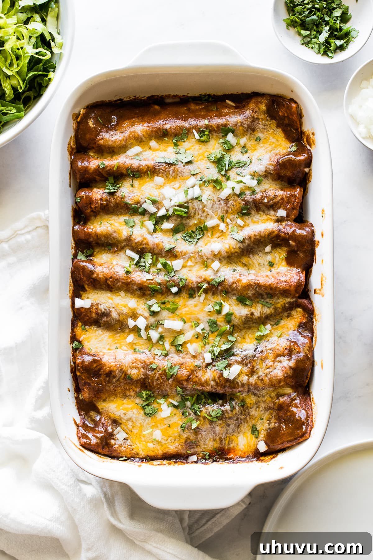 Hearty Beef Enchilada Fiesta 7 Ground beef enchiladas in a baking dish topped with cilantro and onions.