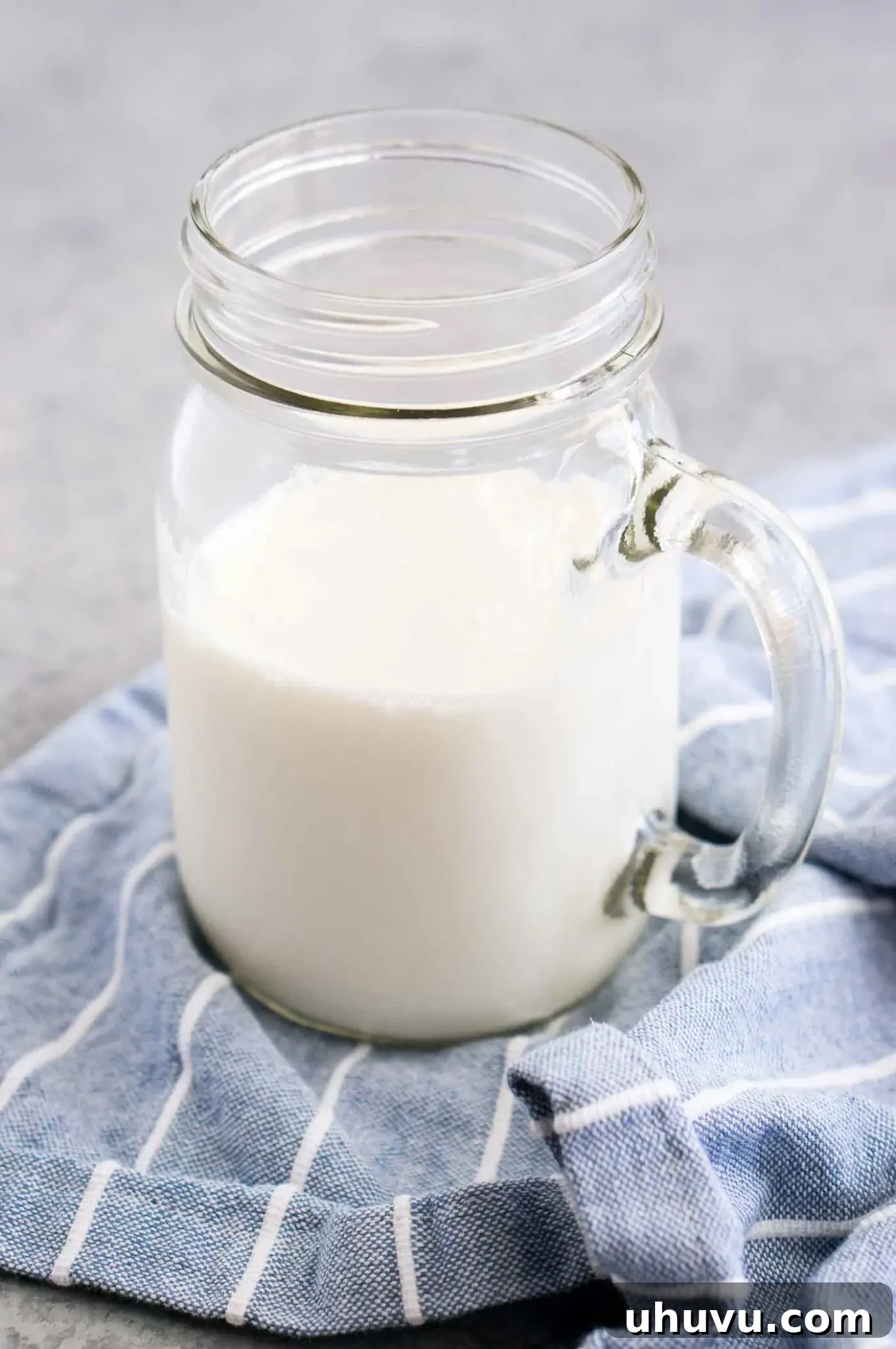 Close up of tangy homemade buttermilk in a clear glass jar, showing its creamy texture