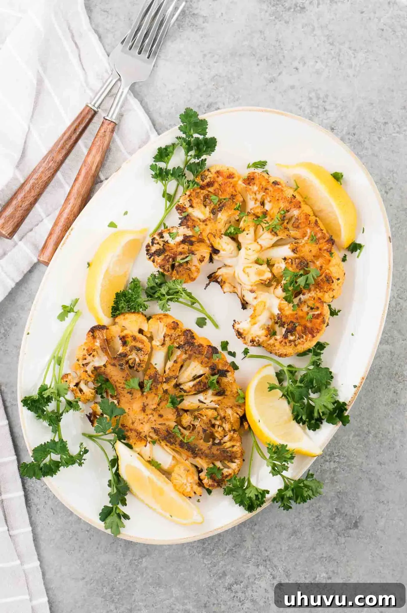 oven roasted cauliflower steaks with lemon slices on a platter
