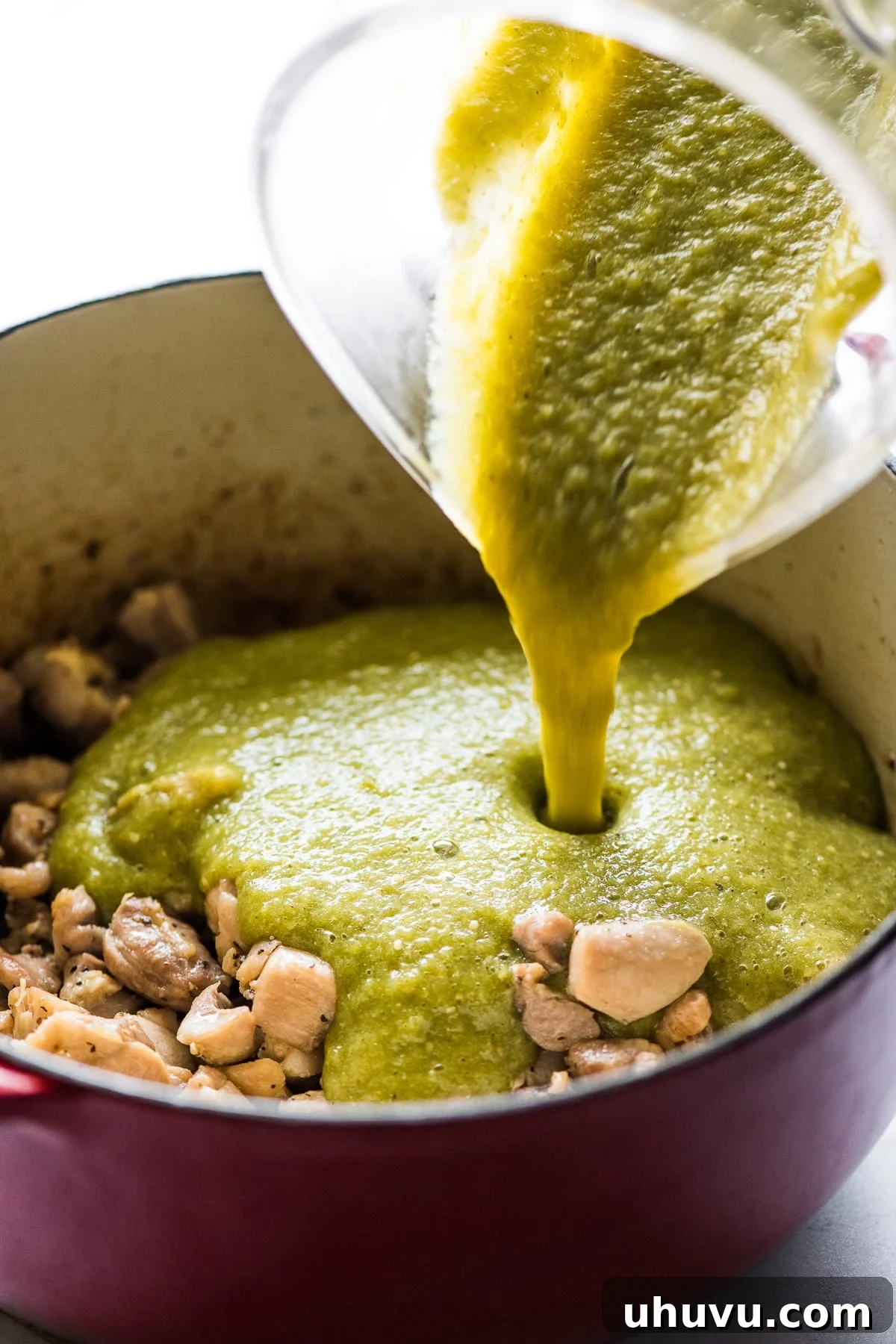 Emerald Chicken Verde 4 The vibrant green tomatillo and chile sauce is carefully poured over beautifully browned chicken thighs in a large pot, ready to be simmered.