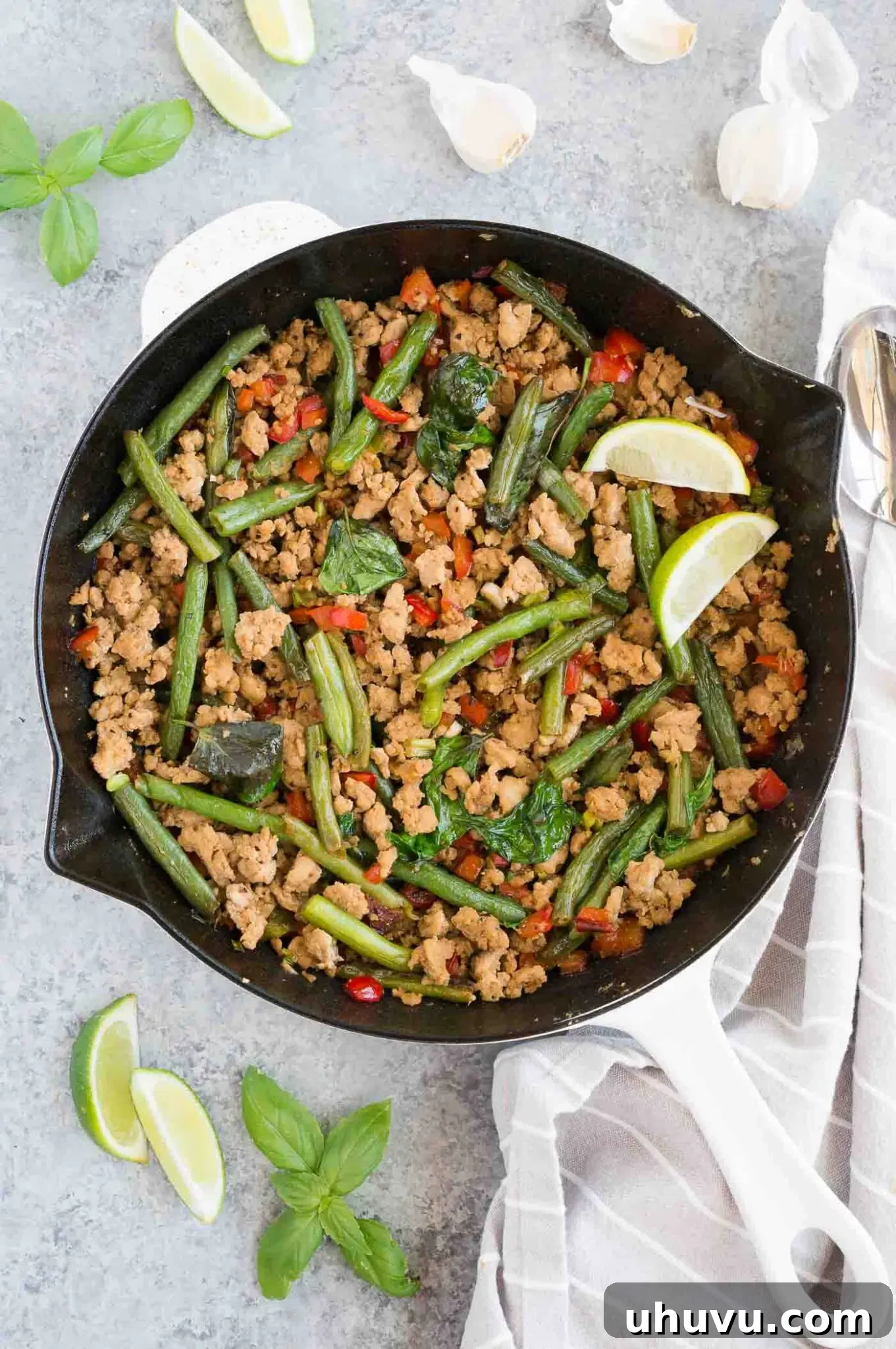 Thai chicken and green beans stir fry in a skillet, nearly ready to serve.
