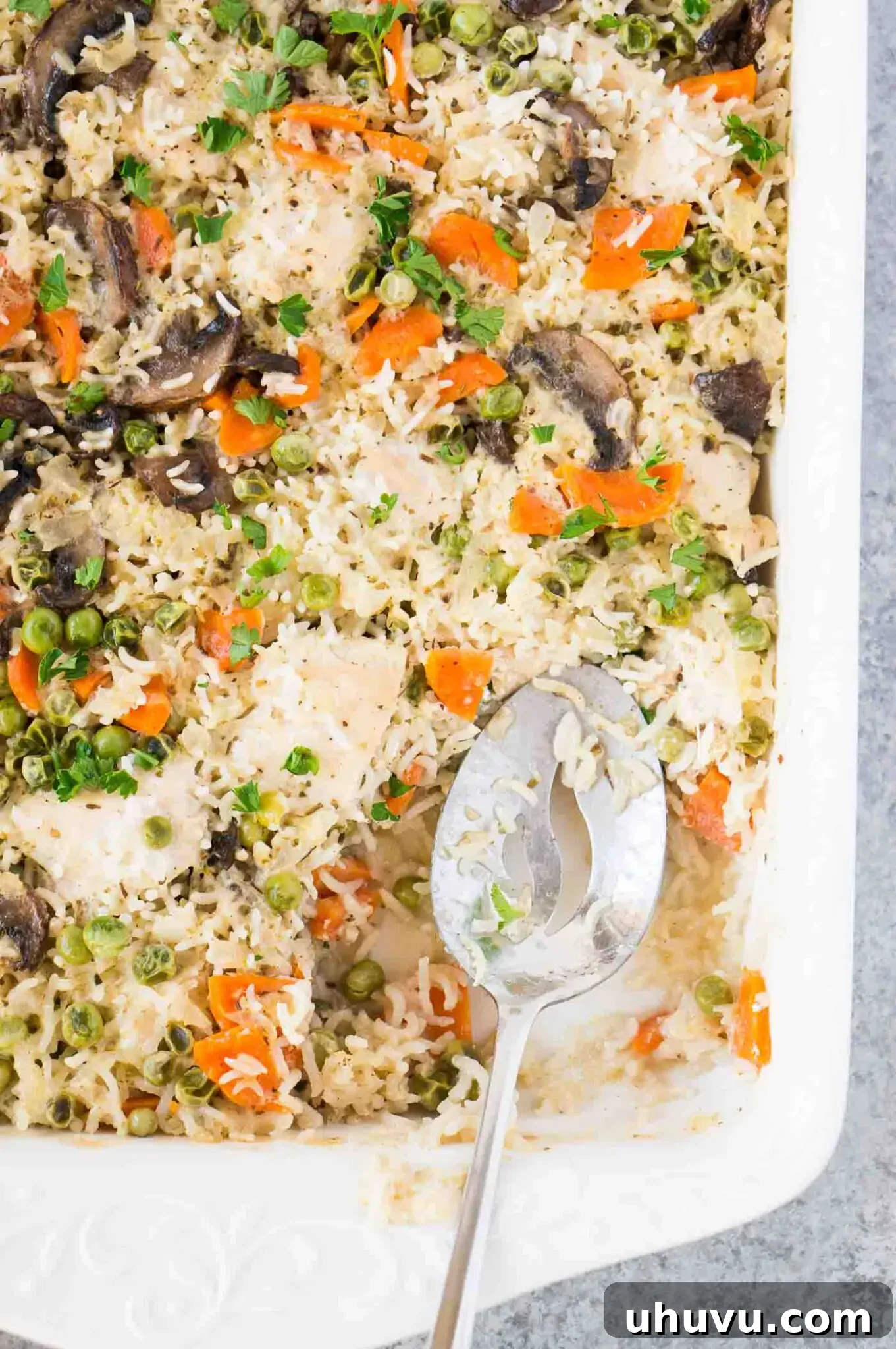 Creamy chicken and rice bake with a serving spoon in casserole dish