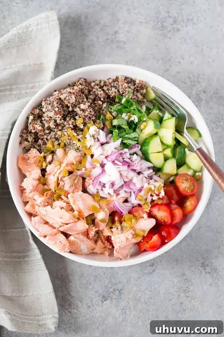 mixing bowl with cooked quinoa, salmon, and vegetables for salad