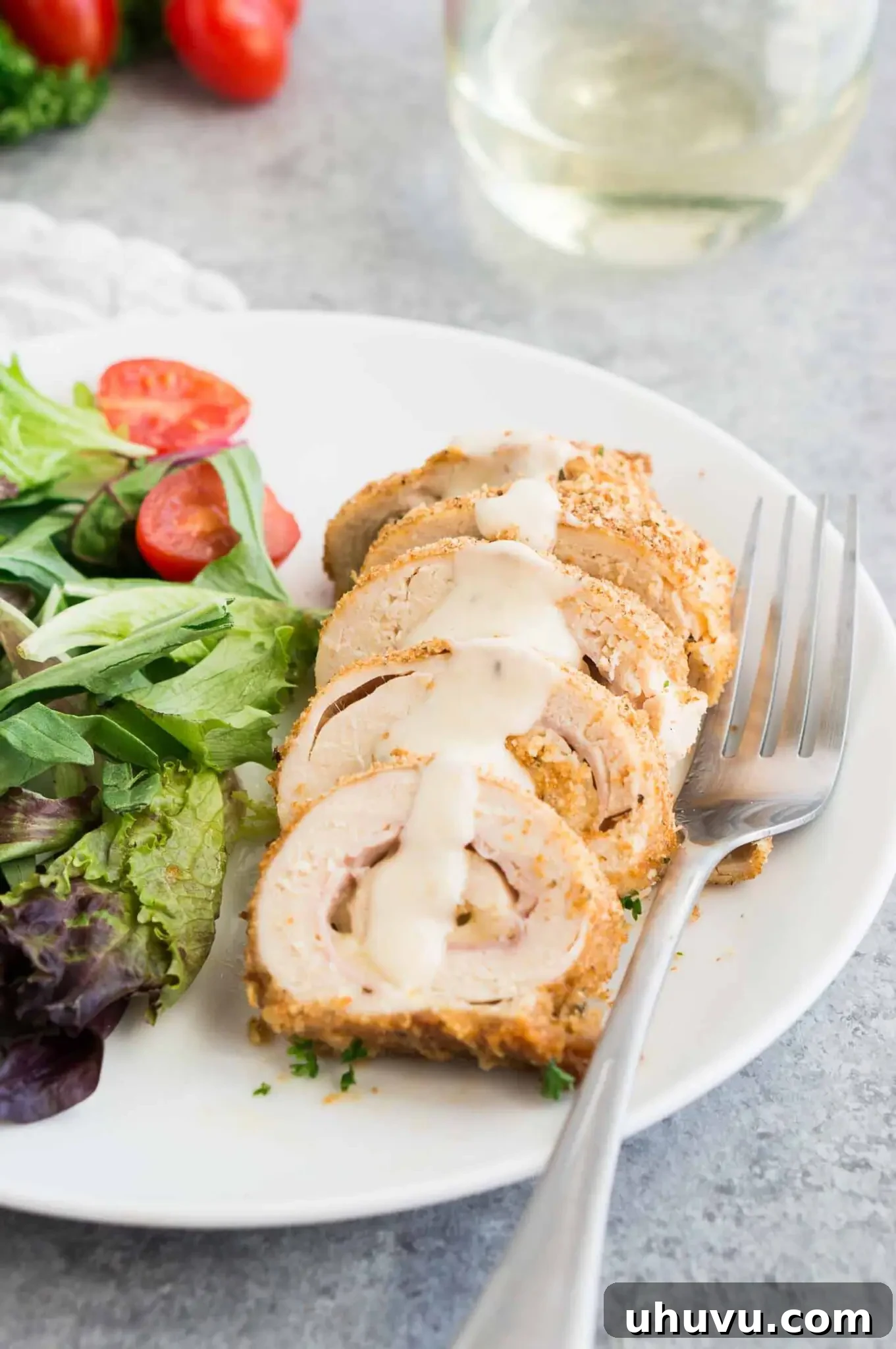 Homemade Chicken Cordon Bleu with creamy Dijon sauce and a side salad on a plate