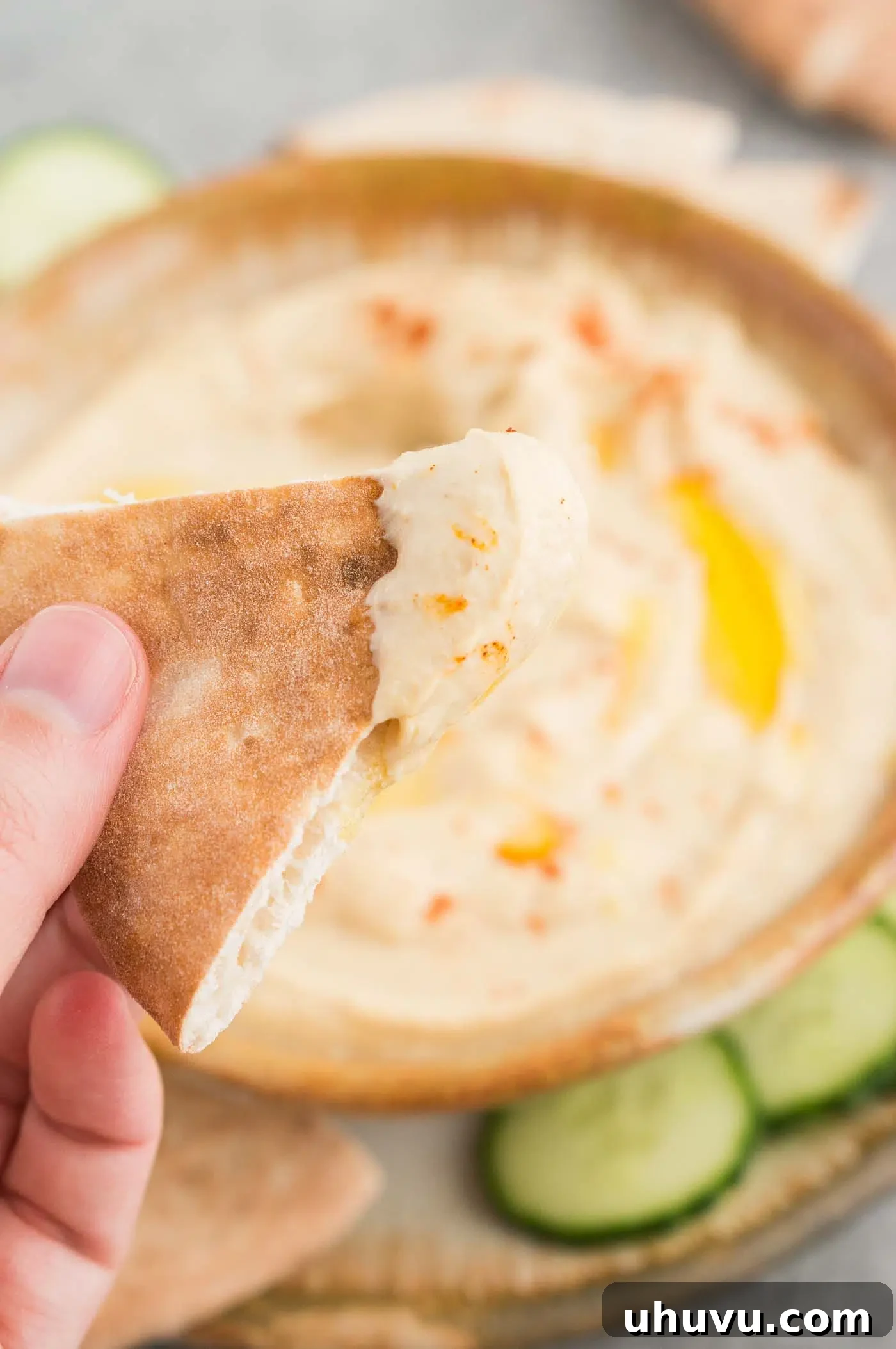 close up image of hummus in a bowl and slice of pita