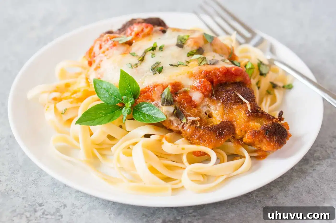 Golden Crispy Parmesan Chicken 3 chicken parmesan over linguini pasta on a plate