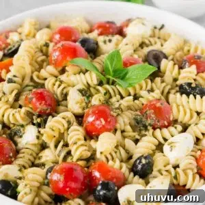 Vibrant Pesto Pasta Salad 7 close up image of pesto pasta salad with tomatoes and olives and mozzarella balls