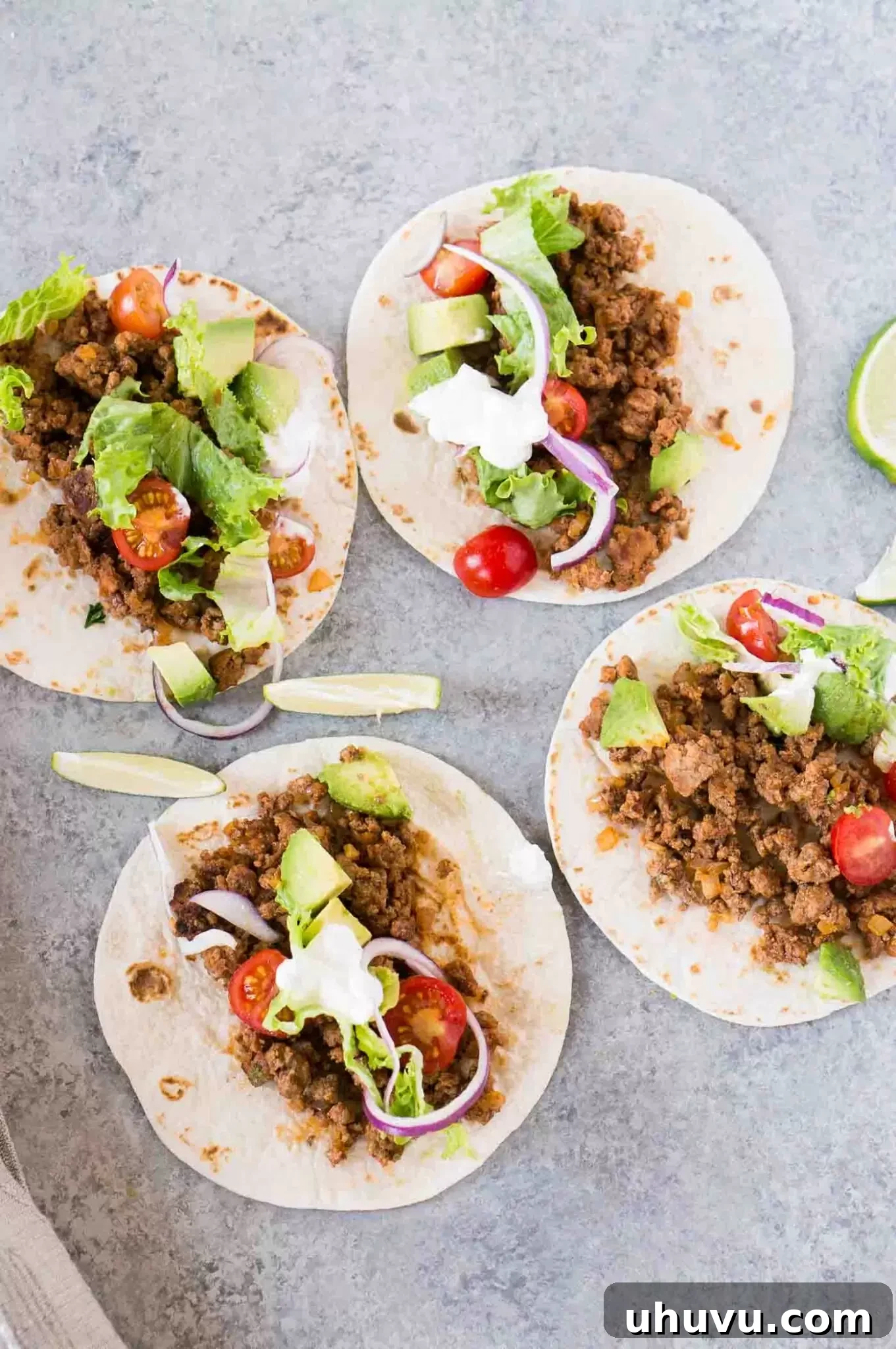 Close-up shot of perfectly cooked and seasoned ground beef taco filling nestled in soft tortillas, awaiting toppings.