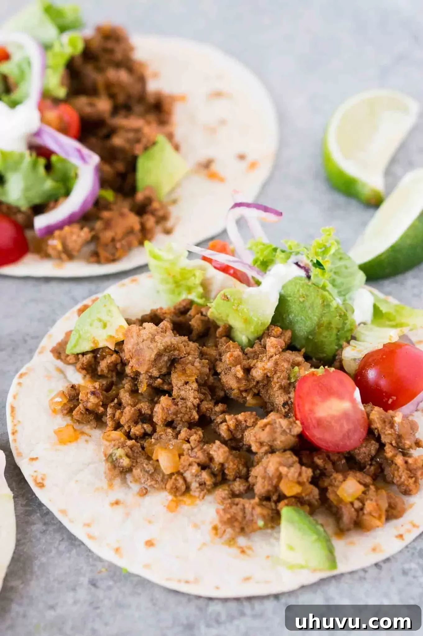 A close-up of a delectable ground beef taco generously filled with meat and adorned with fresh, vibrant toppings.