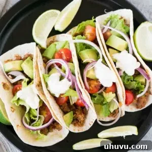 four tacos on a plate with lime wedges