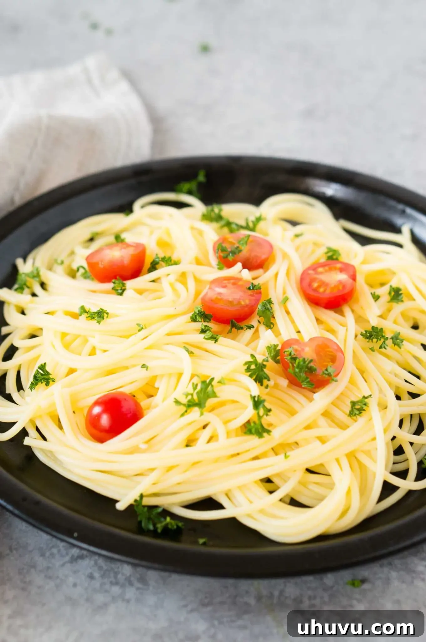 Perfectly cooked spaghetti with fresh cherry tomatoes and herbs on a white plate, ready to be served.