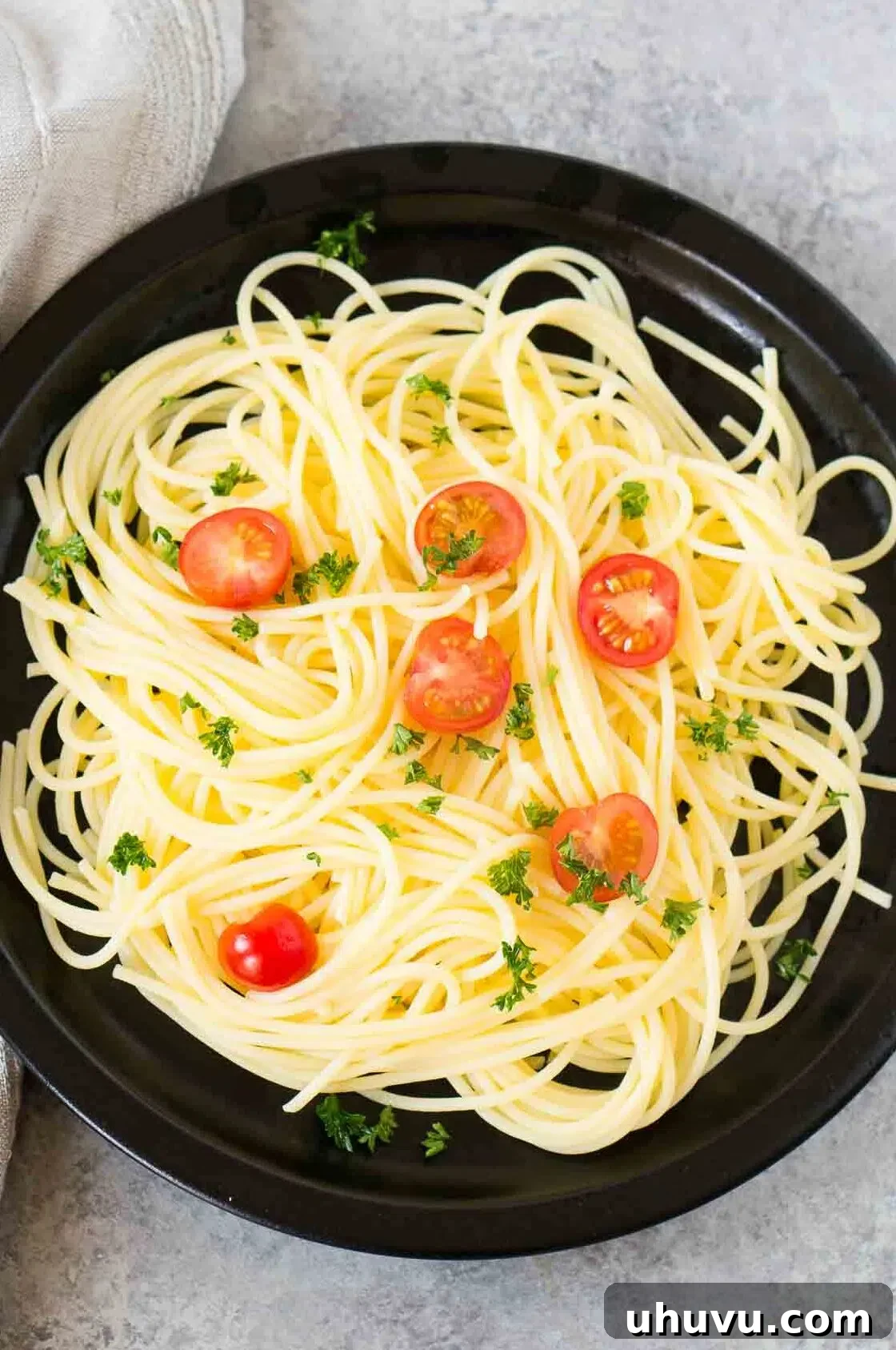 Freshly drained, perfectly cooked pasta ready to be tossed with sauce, shown on a dark plate.