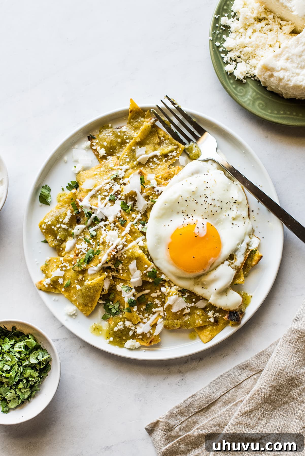 Emerald Chilaquiles 7 Chilaquiles Verdes generously topped with a perfectly cooked sunny-side-up egg, ready for a delicious breakfast.