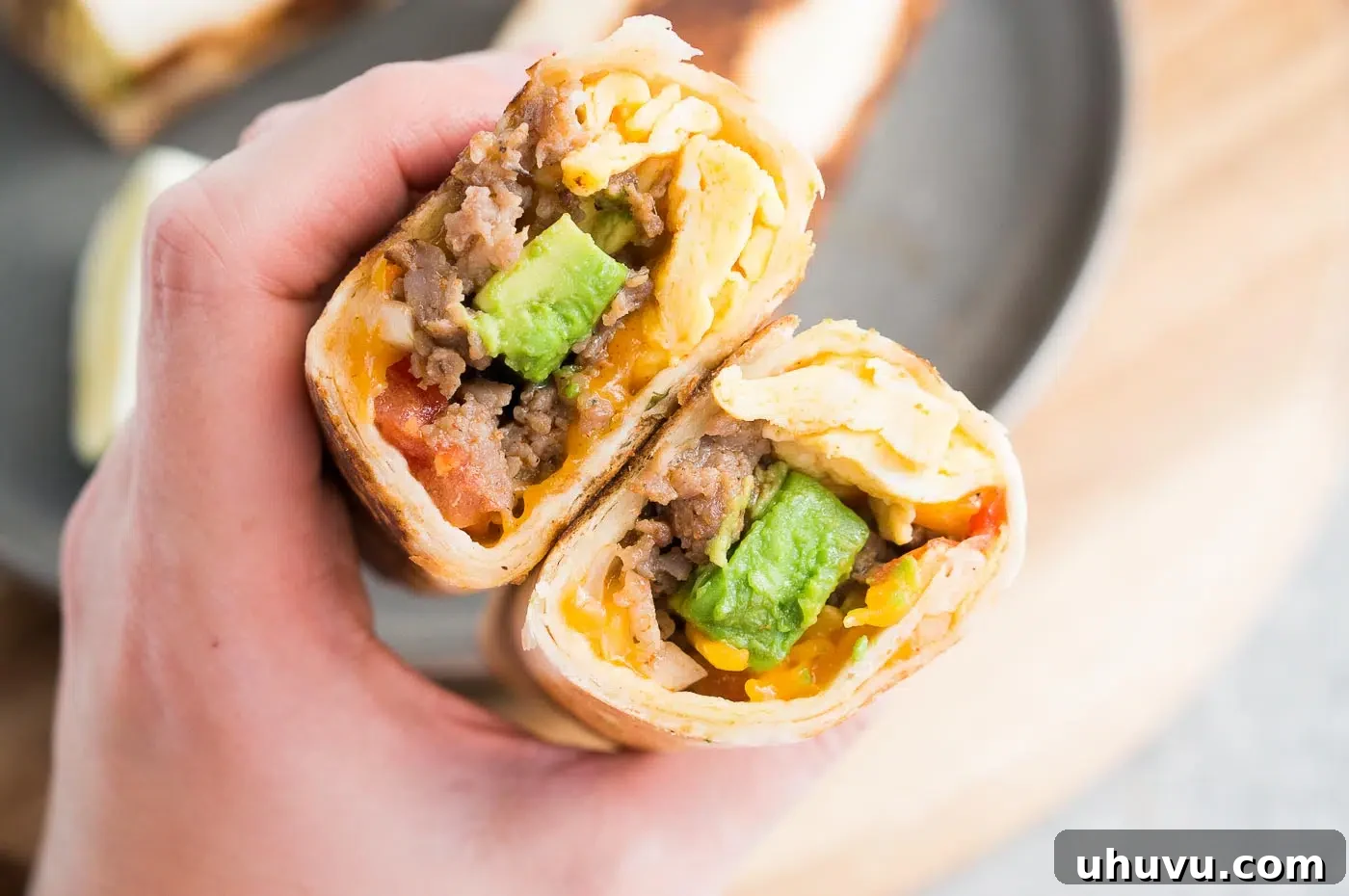 A hand holding a perfectly wrapped breakfast burrito, showcasing its golden-brown exterior