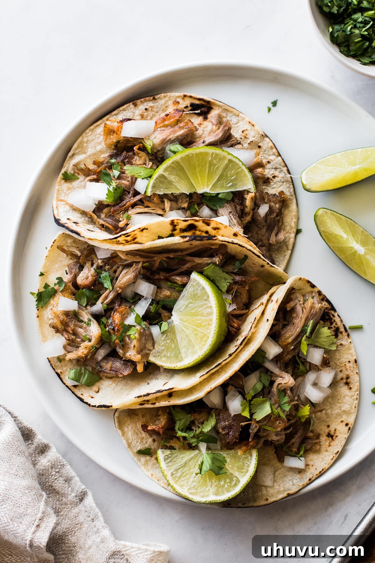 Lightning-Fast Crispy Carnitas 8 Instant Pot carnitas in tacos topped with onions, cilantro, and lime wedges.