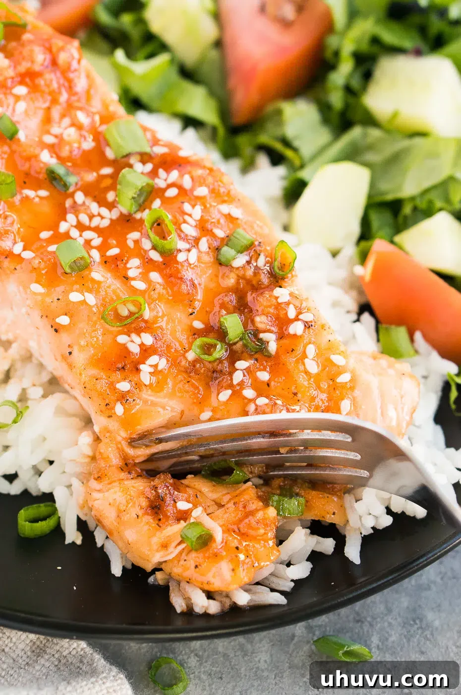 A close-up shot of a fork gently flaking a perfectly cooked honey sriracha glazed salmon fillet, demonstrating its tenderness.