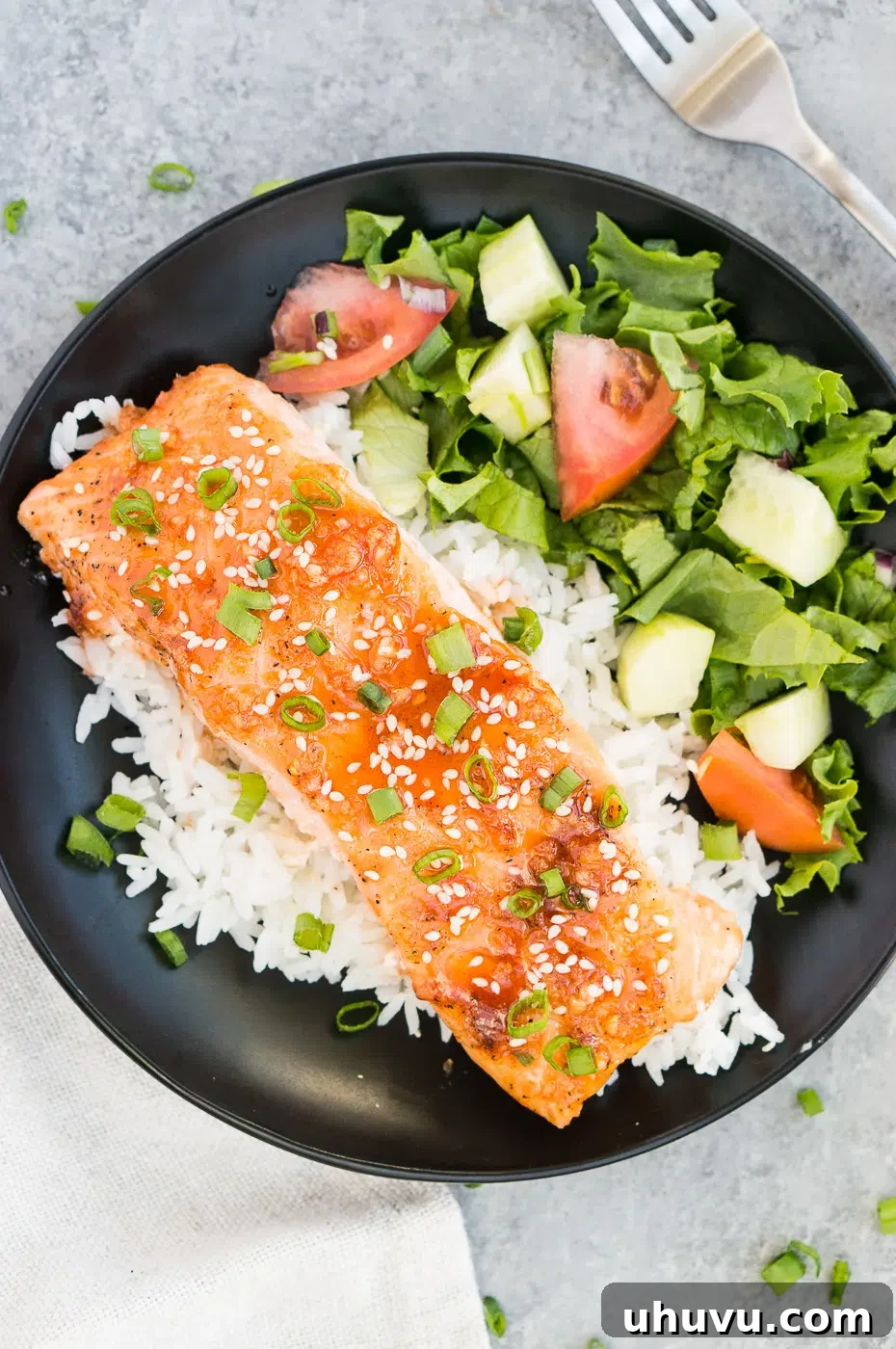 A beautifully plated baked salmon with honey sriracha glaze, served alongside fluffy rice and a crisp green salad, ready to be enjoyed.