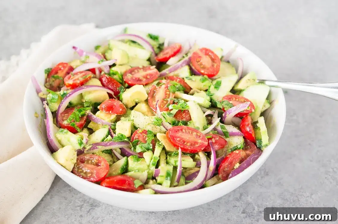 Mixing avocado tomato cucumber salad in a large bowl