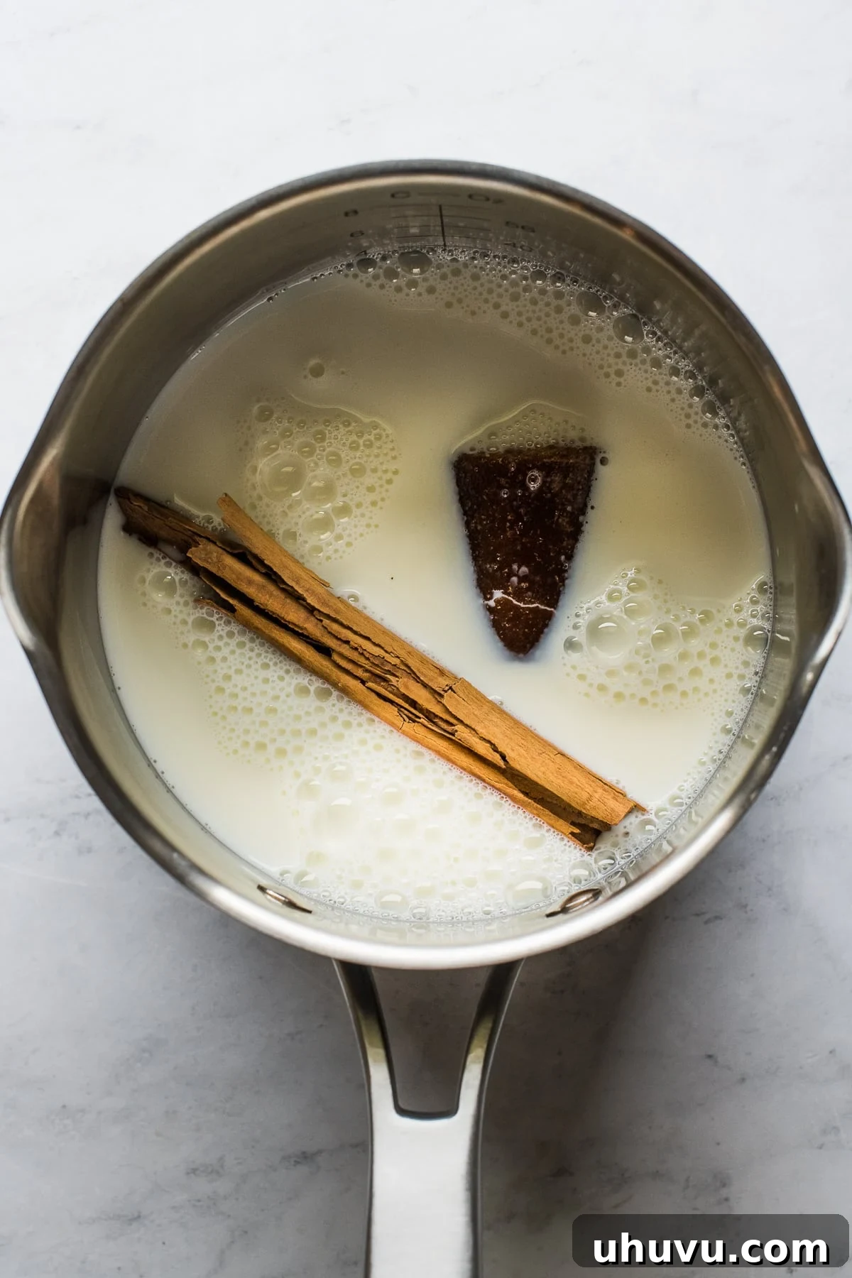 The Comforting Warmth of Mexican Atole 4 Milk, piloncillo, and a cinnamon stick gently simmering in a saucepan on the stovetop.
