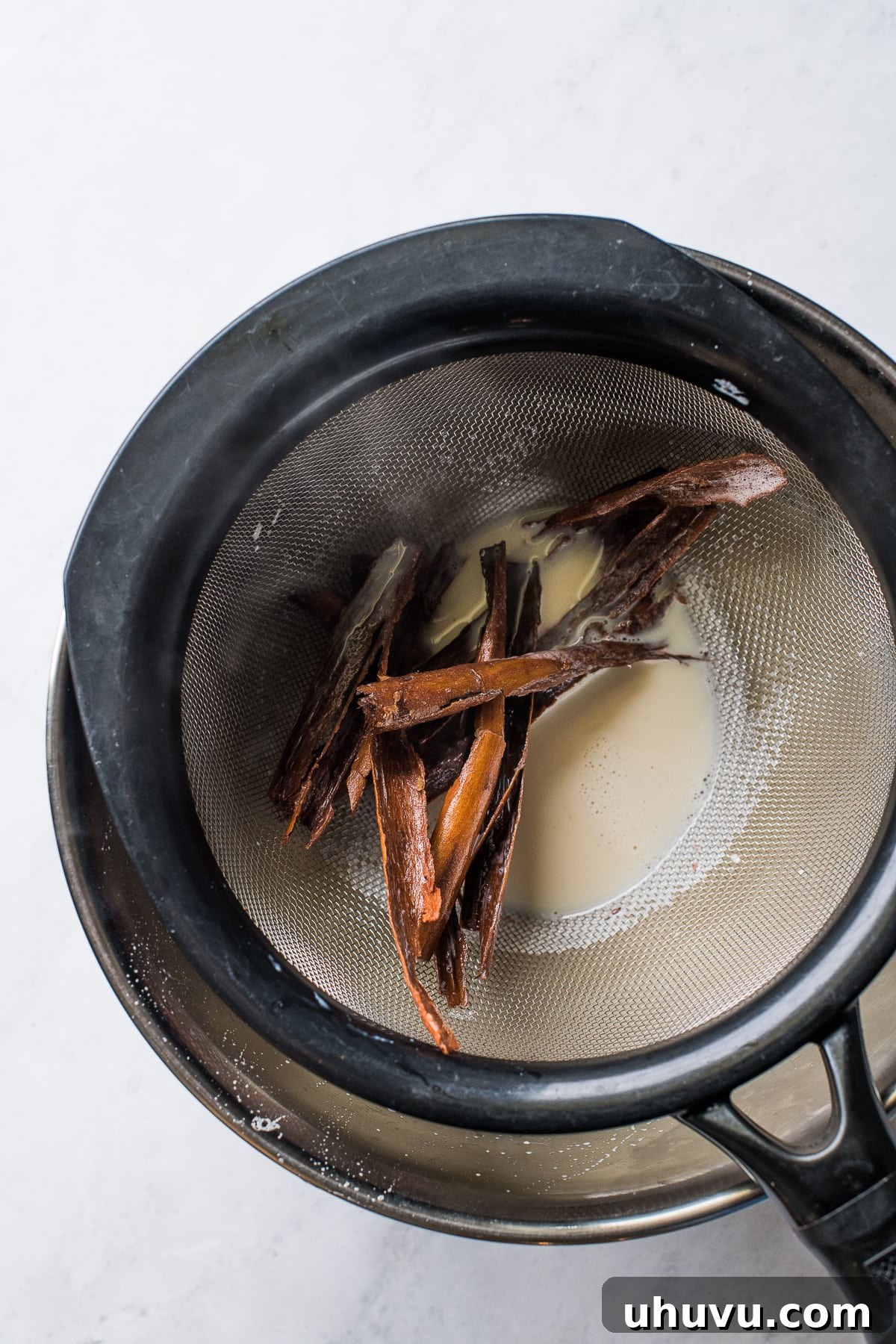The Comforting Warmth of Mexican Atole 5 Small pieces of a cinnamon stick captured in a strainer after being removed from the atole milk mixture.