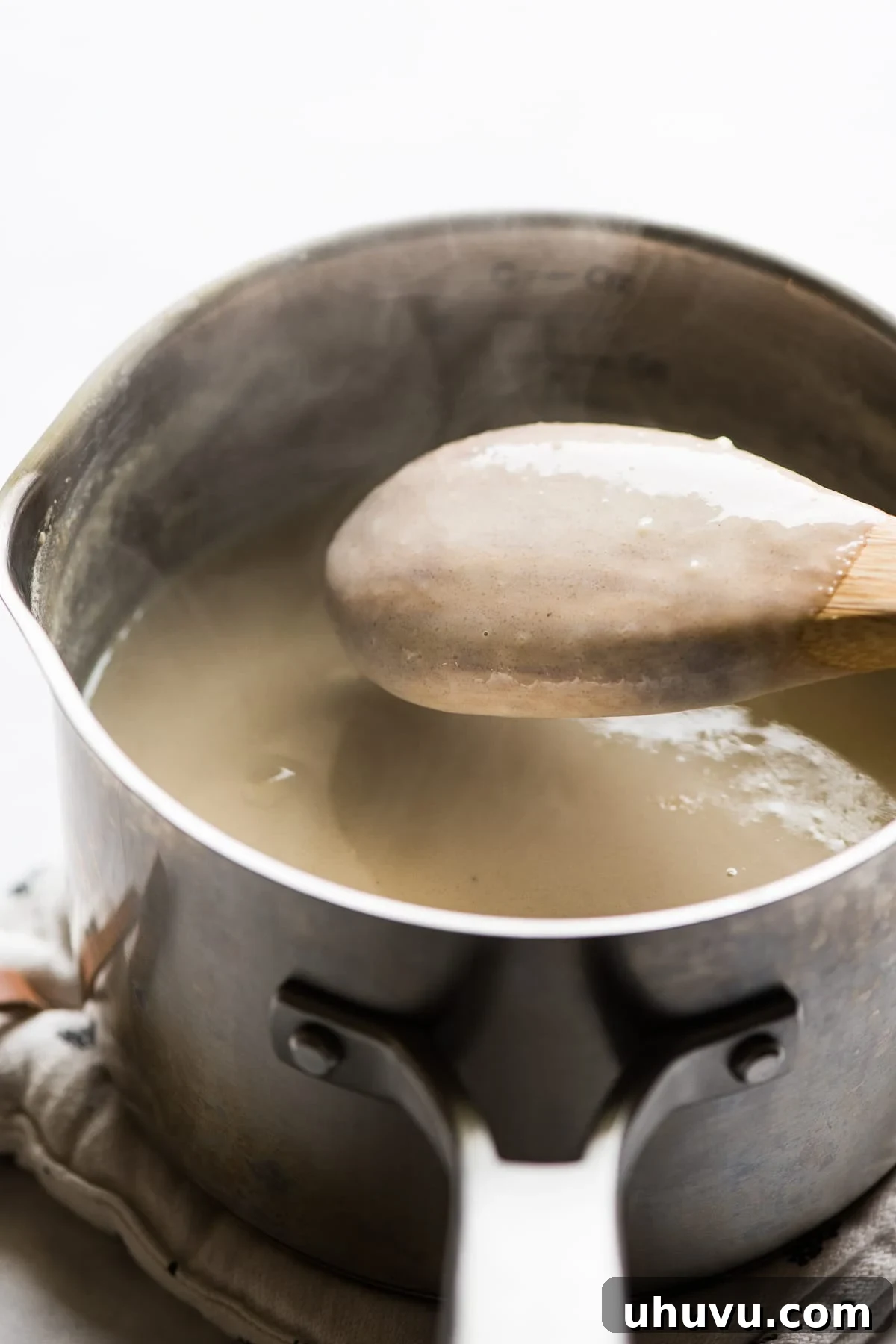 The Comforting Warmth of Mexican Atole 8 A wooden spoon lifted from the pot, showing a rich, thickened atole coating its back smoothly, indicating it's ready to serve.