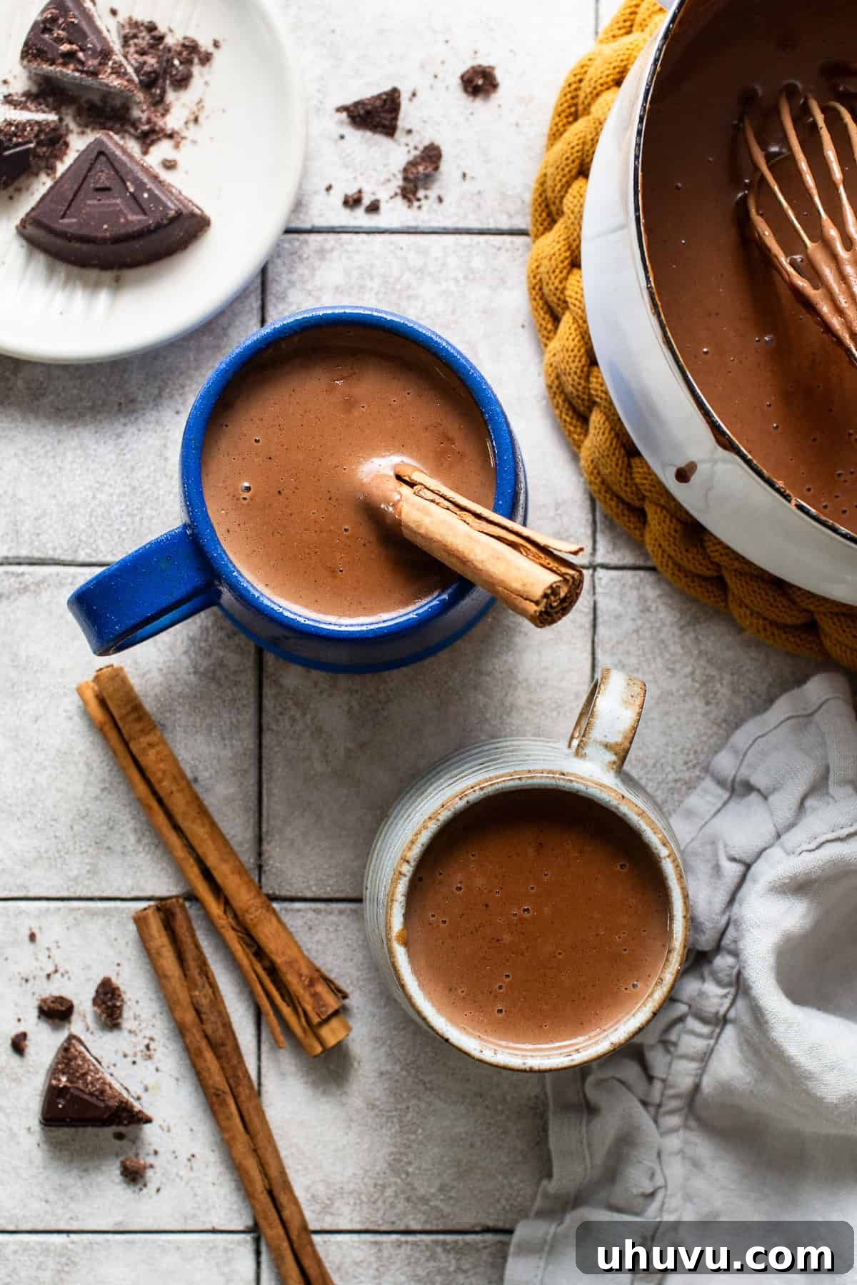 Velvet Corn Chocolate 9 The saucepan filled with champurrado is being served into two separate mugs ready to enjoy.
