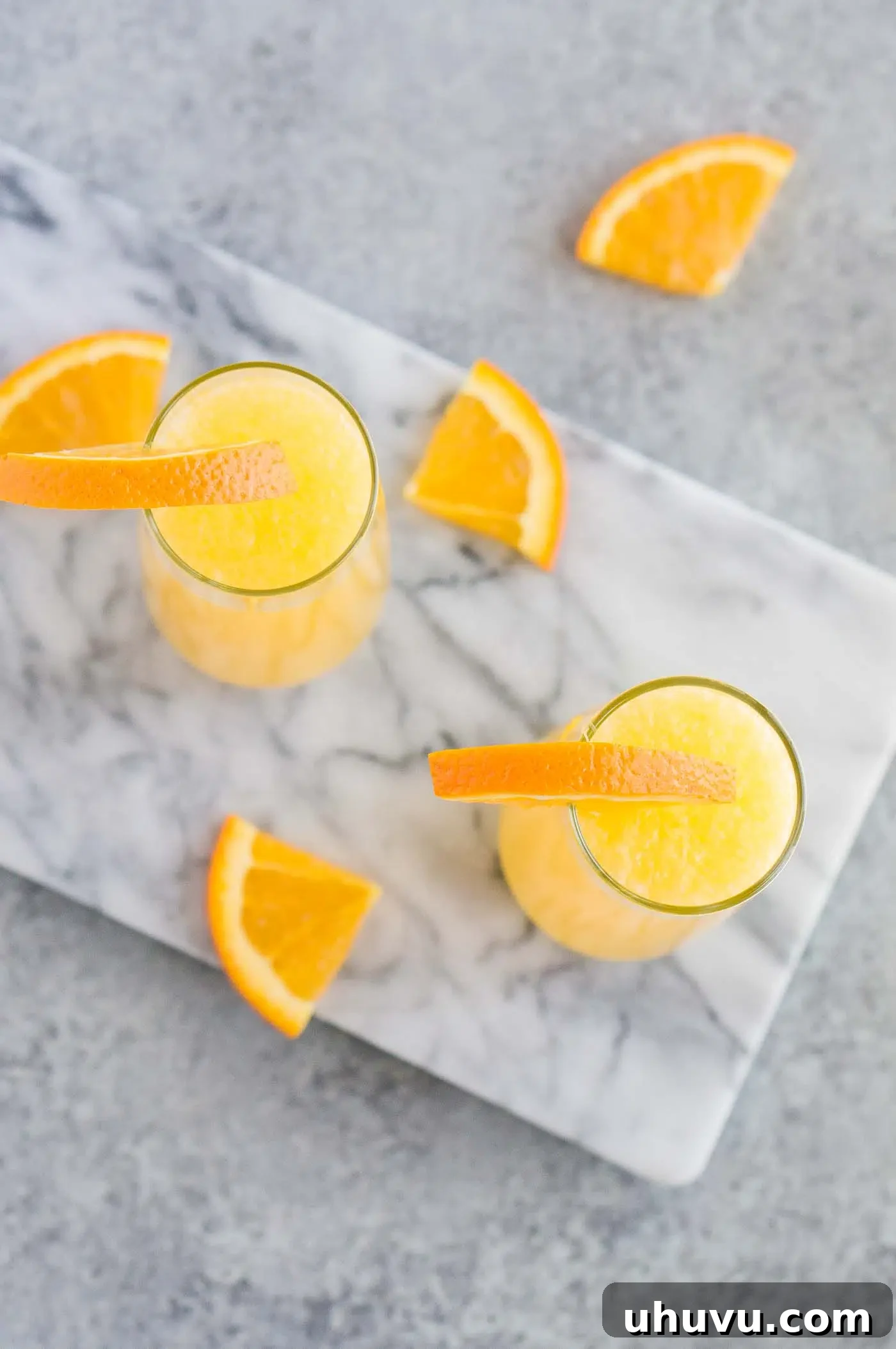 Several mimosa cocktails served in elegant flute glasses, garnished with fresh orange slices, ready for a festive gathering.