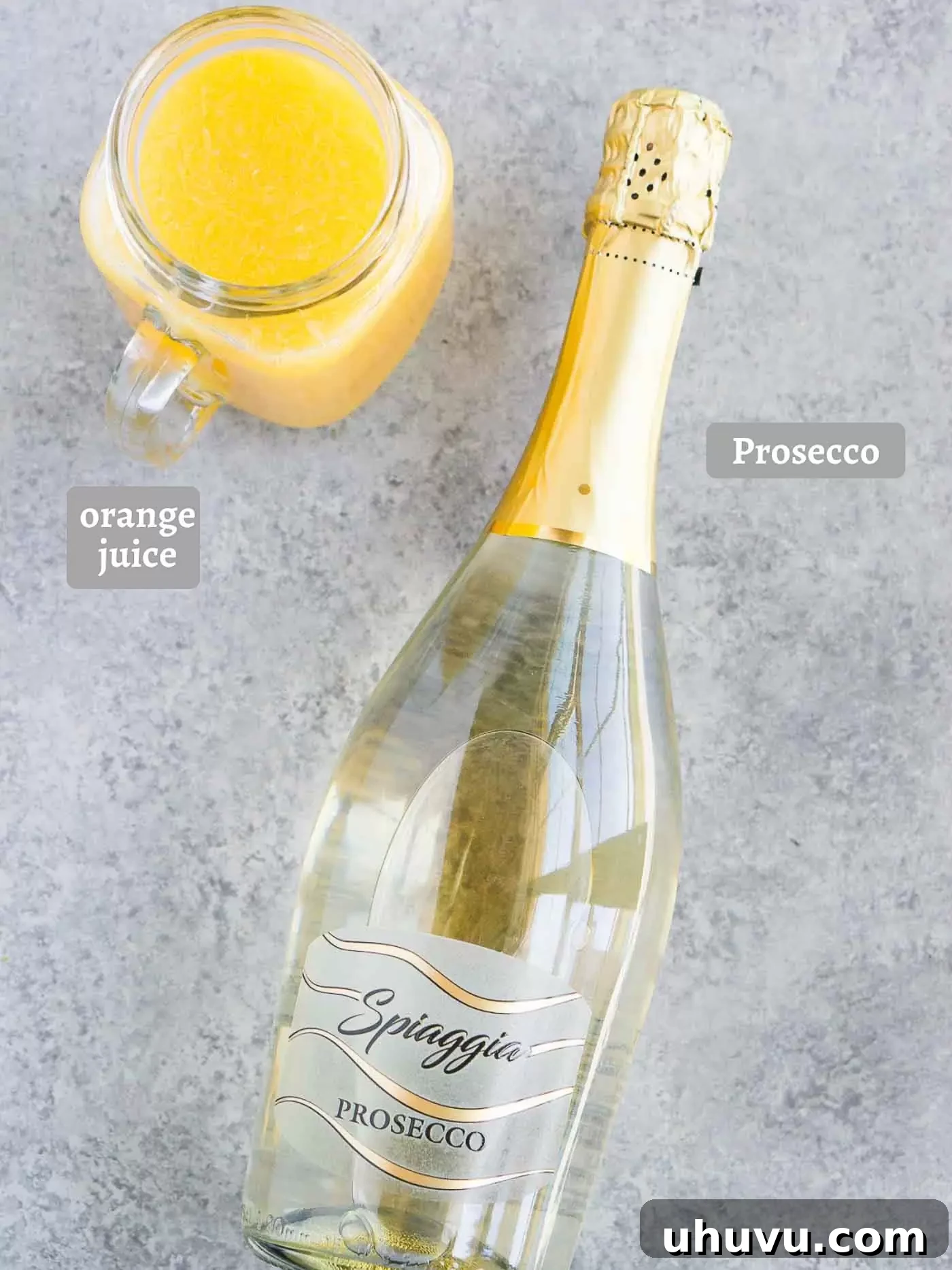 Fresh ingredients for making mimosas, including a bottle of sparkling wine and a glass of orange juice, on a rustic surface, highlighting simplicity and quality.