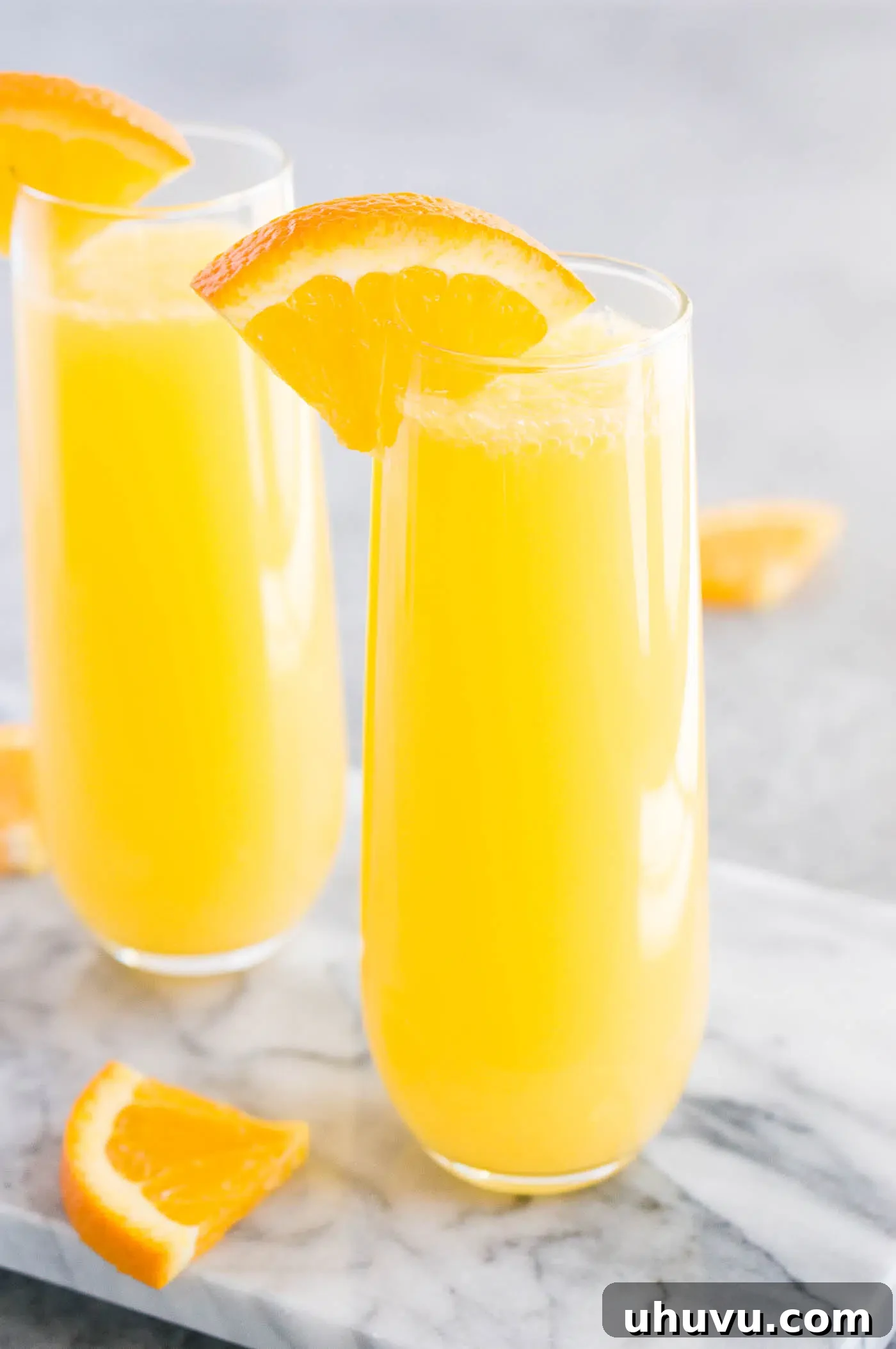 Mimosa cocktails served in elegant flutes, beautifully garnished with orange slices and mint, ready to be enjoyed at a gathering.