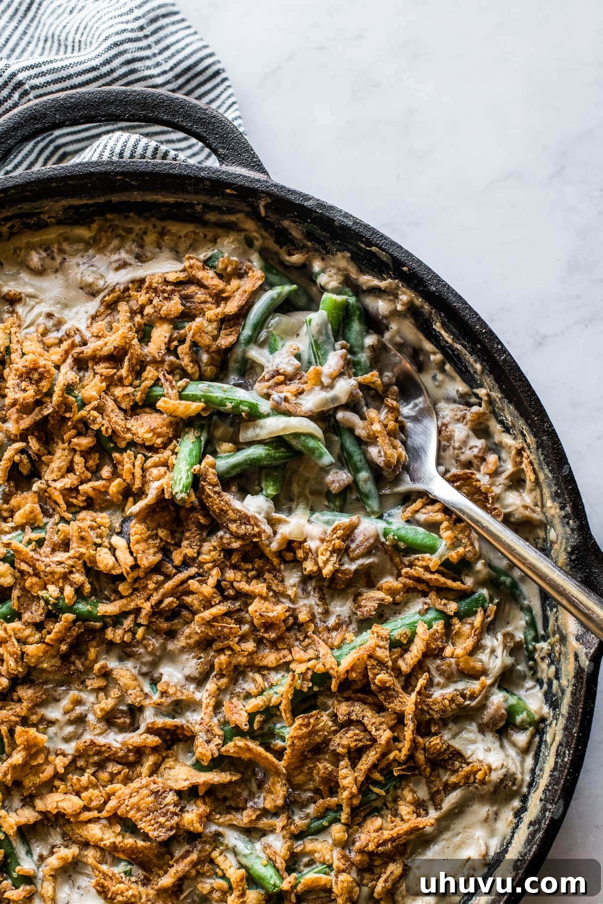 Ultimate Fresh Green Bean Bake 8 A serving spoon gracefully scooping a generous portion of the creamy fresh green bean casserole.