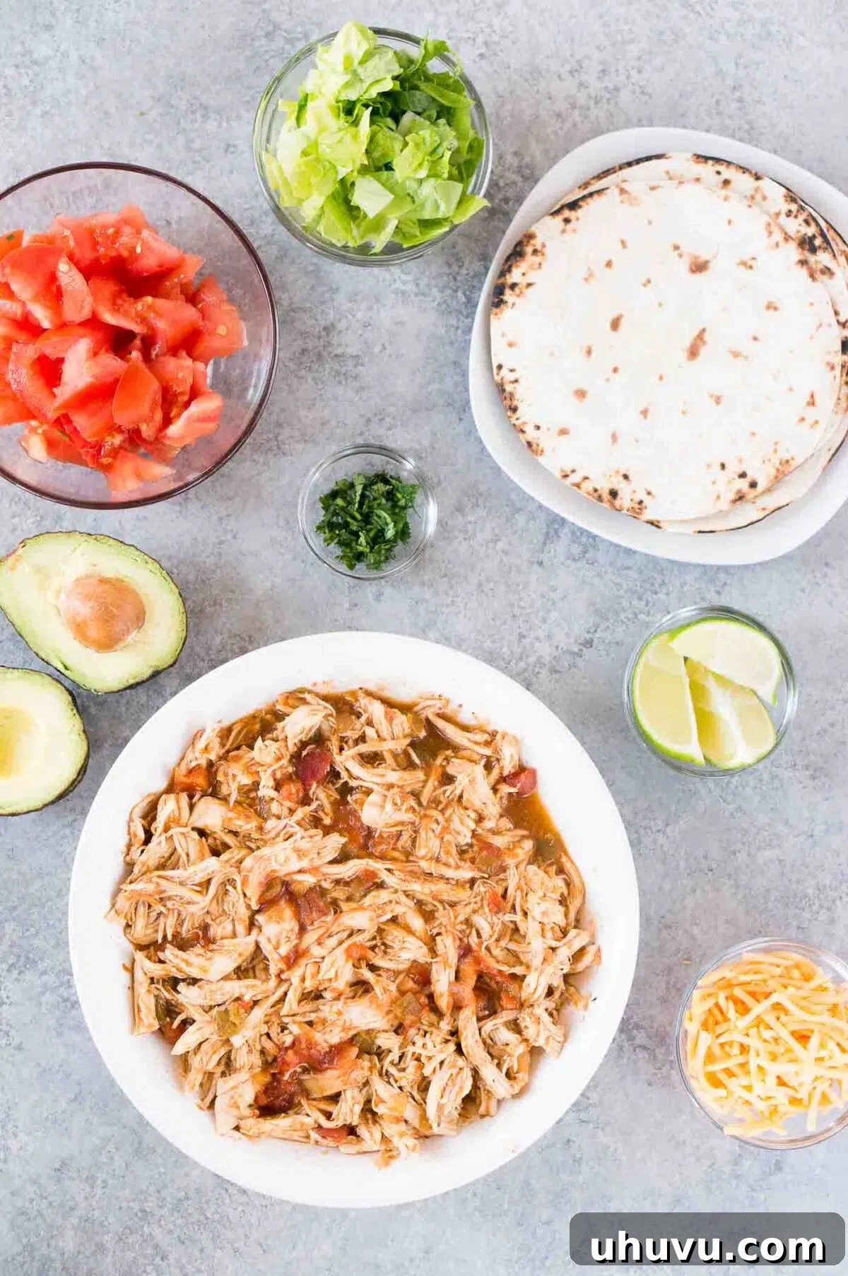 various toppings for chicken tacos including shredded lettuce, cheese, tomatoes, and avocado