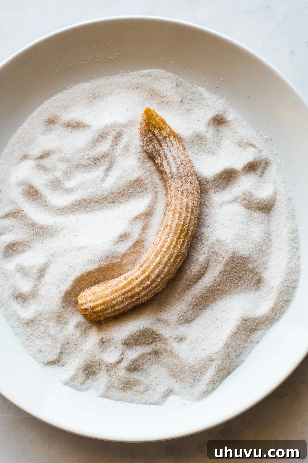 Authentic Churros From Scratch 7 Churros being covered in cinnamon sugar coating.