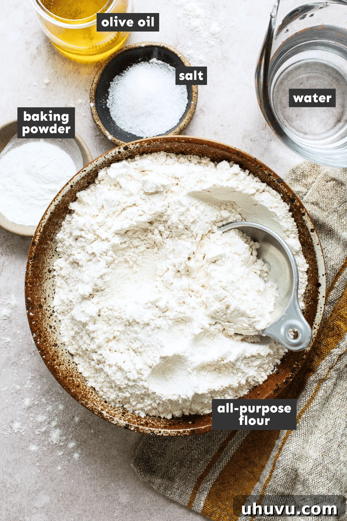 Separate bowls of all-purpose flour, baking powder, salt, olive oil, and warm water for making flour tortillas