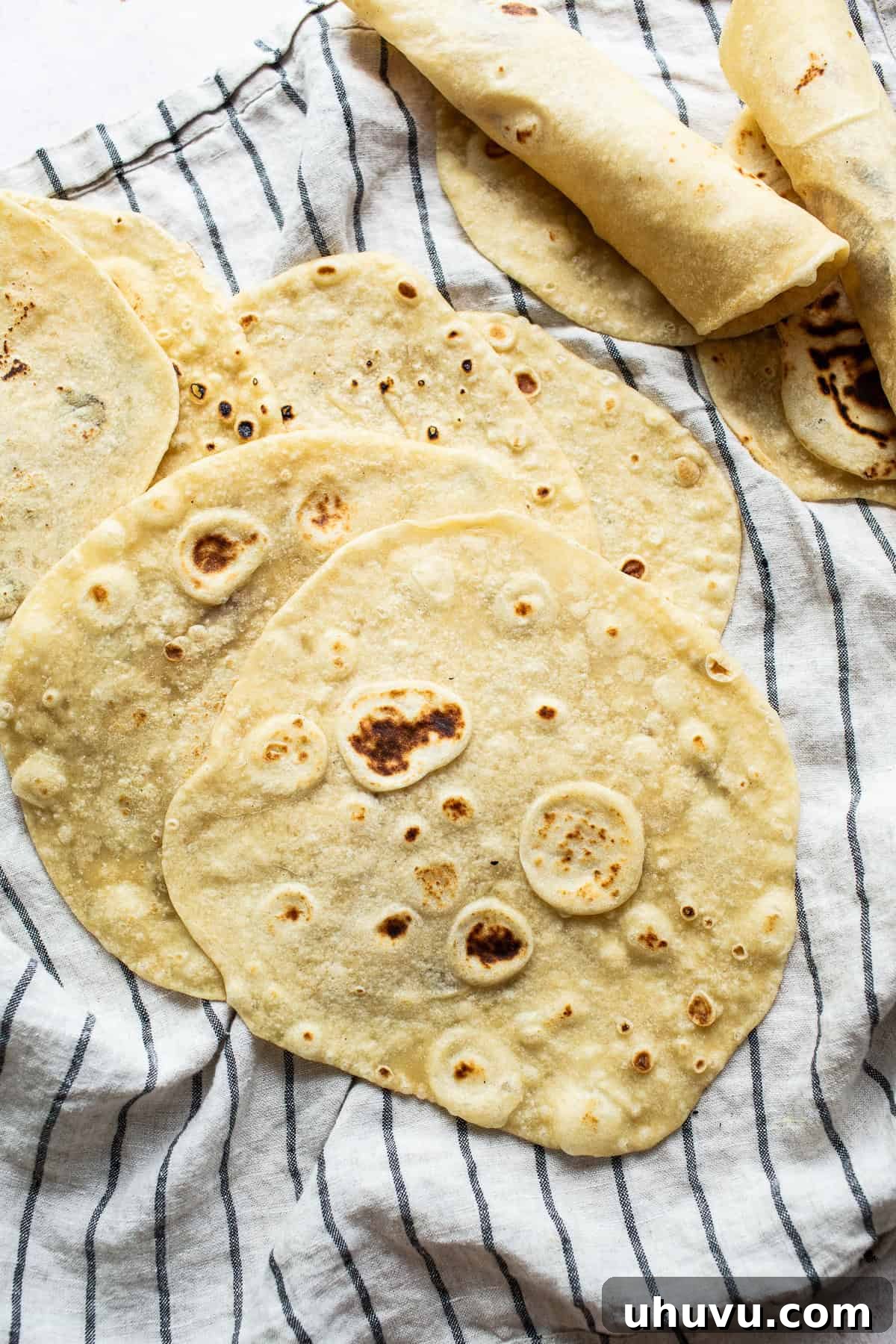A stack of perfectly cooked, soft flour tortillas ready to be enjoyed, showing golden brown spots