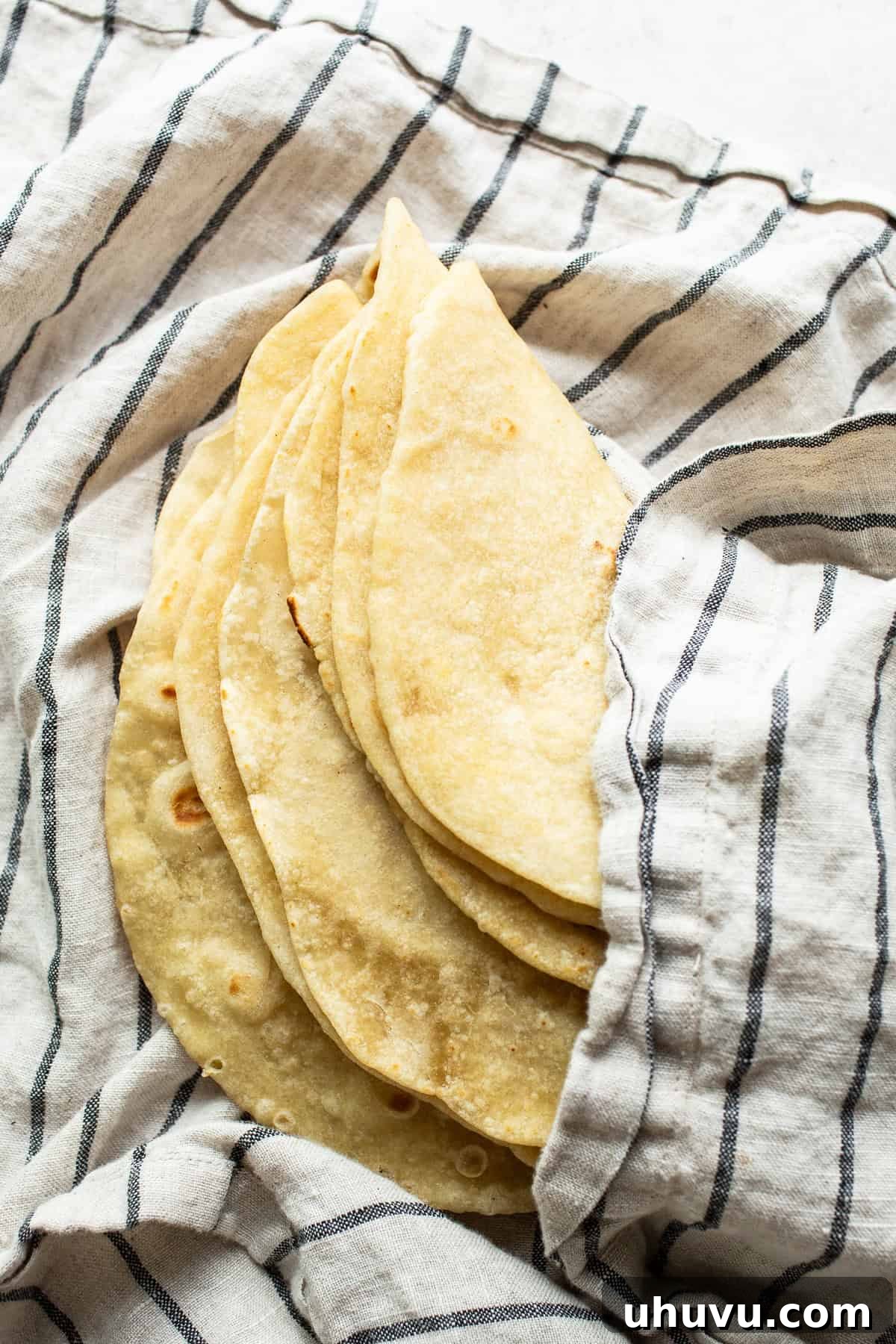 Flour tortilla dough being kneaded in a stand mixer with a dough hook attachment