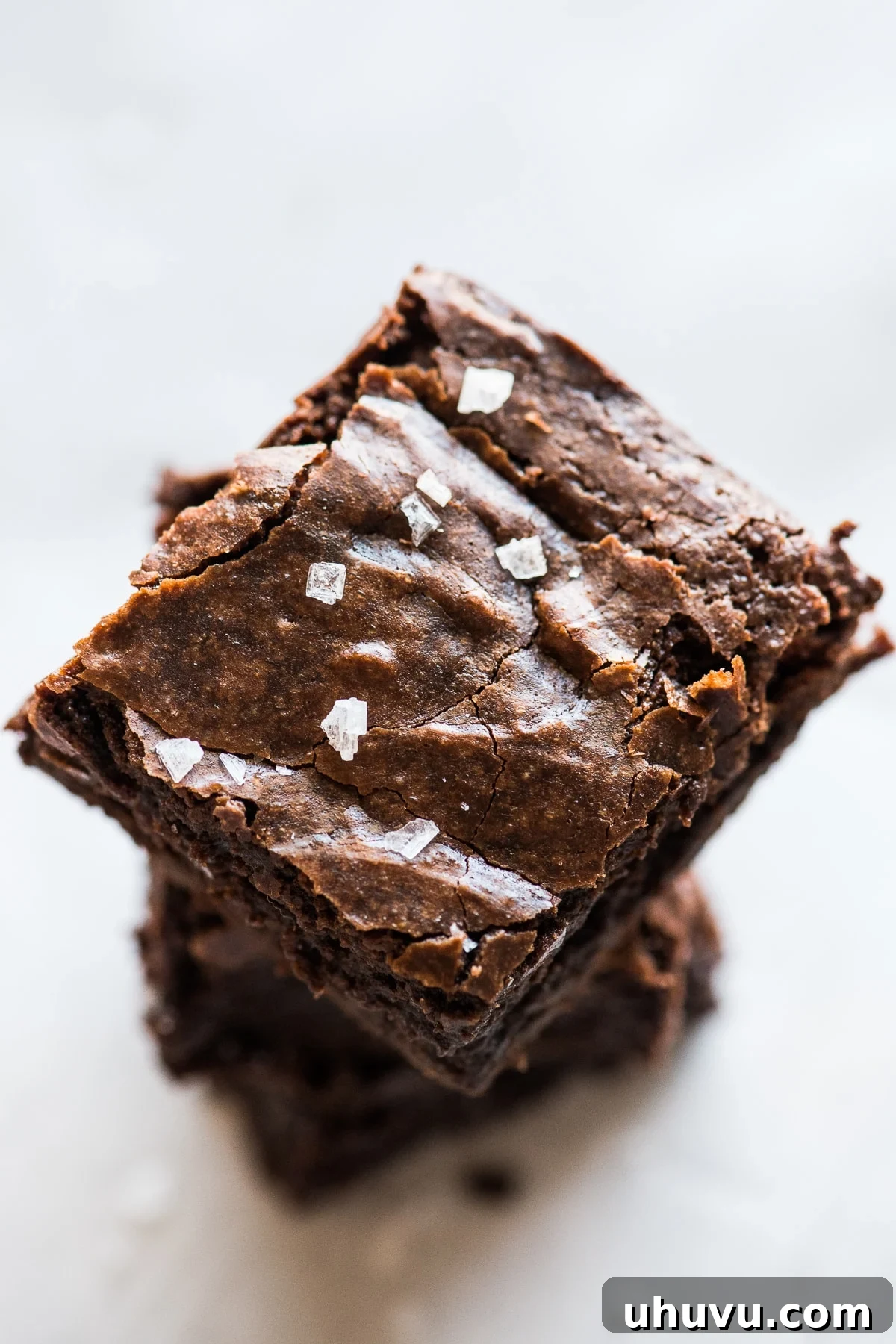 Aztec Chocolate Brownies 5 A single Mexican brownie with a perfectly crinkled top, sprinkled with flaky sea salt, on a light surface.