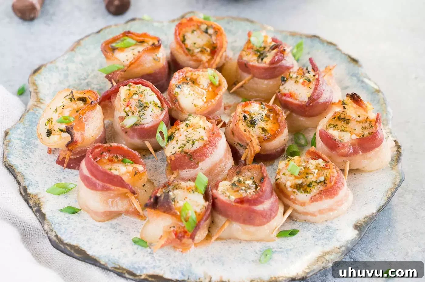 A close-up of beautifully baked scallops wrapped in crispy bacon, garnished and ready to serve.