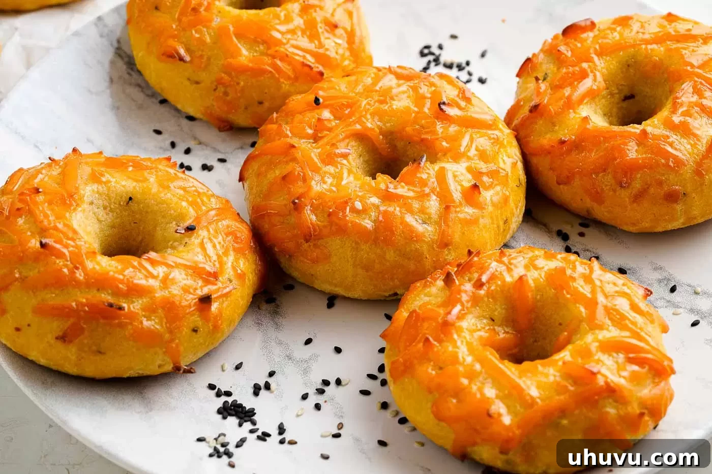 Two freshly baked keto cheese bagels on a light colored plate, ready to be enjoyed.